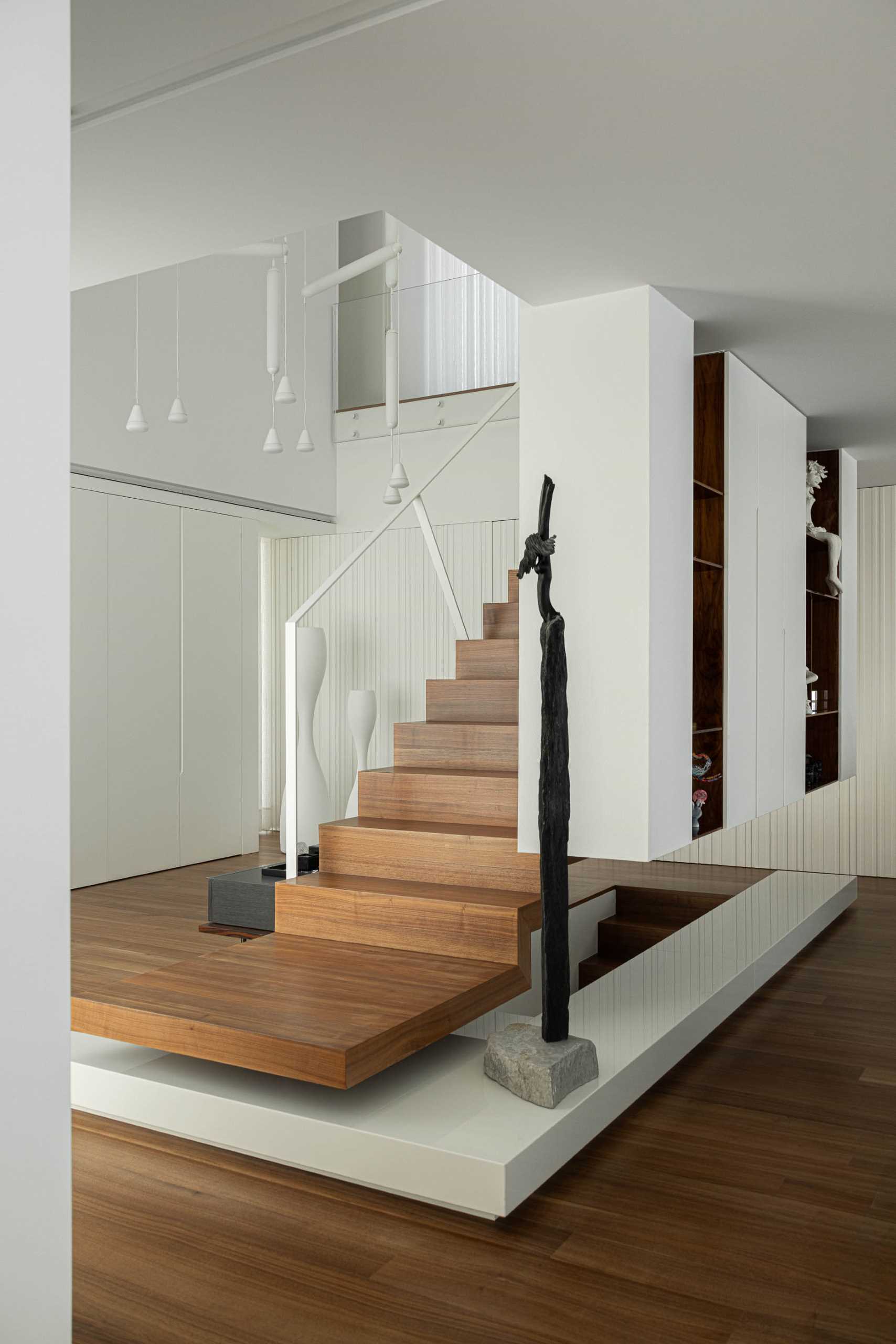 Wood stairs with white handrails connect the social areas of the home with the more private spaces upstairs.