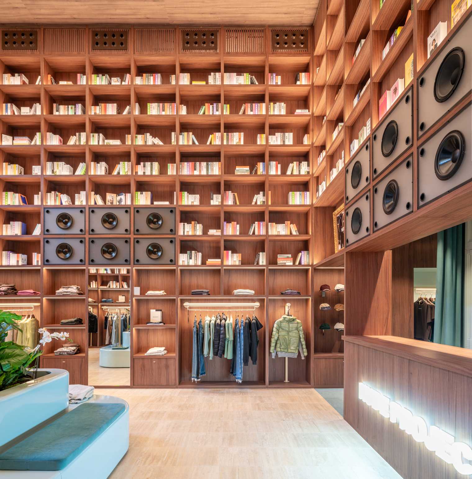 A modern streetwear retail store with 19-foot-high wooden bookshelves, a DJ booth, and a fitting room with baby blue accents.