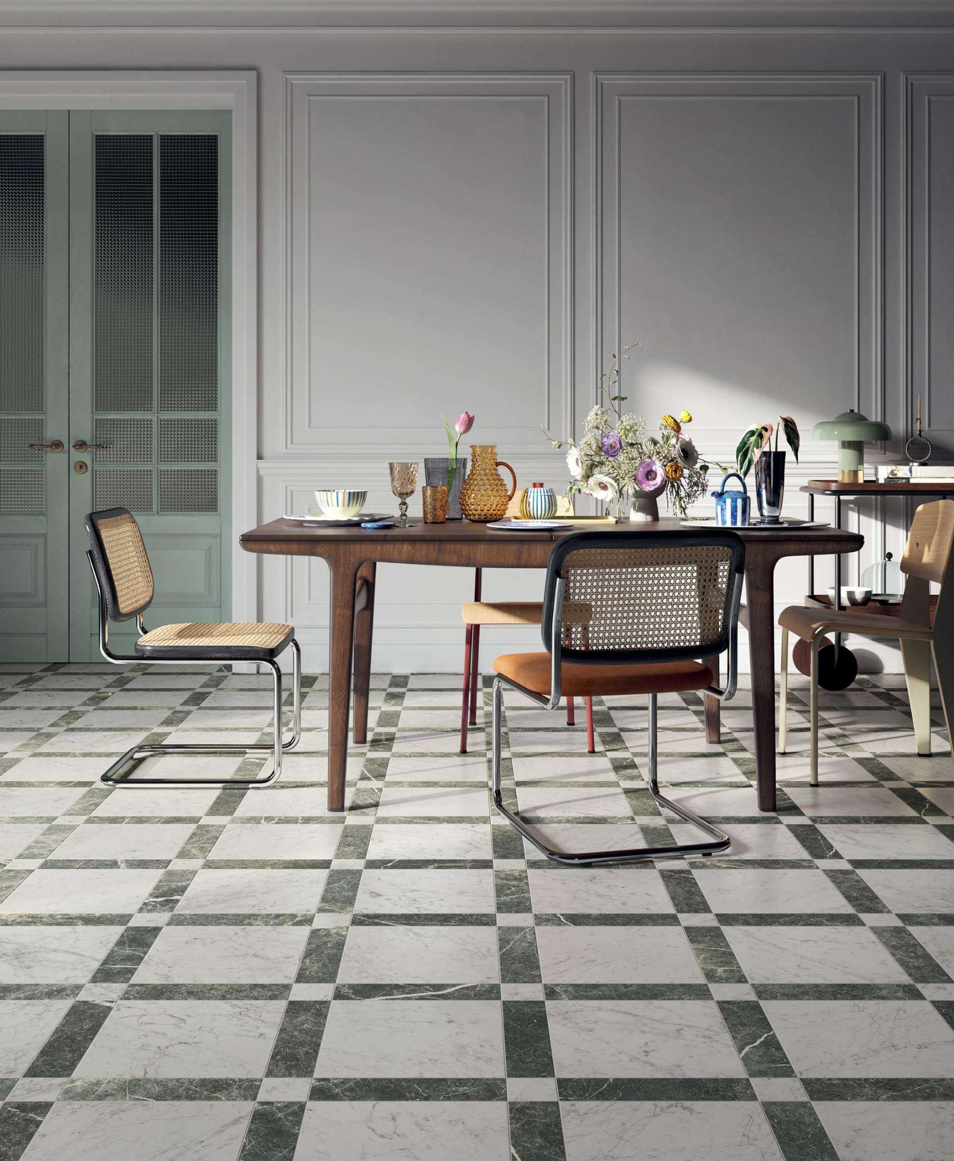 Green-veined marble tiles bordered in a grid layout offer a fresh, tailored take on traditional checkerboard floors. Paired with classic panelled walls and midcentury dining pieces, this patterned tile adds structure and quiet luxury to a soft-toned dining room.