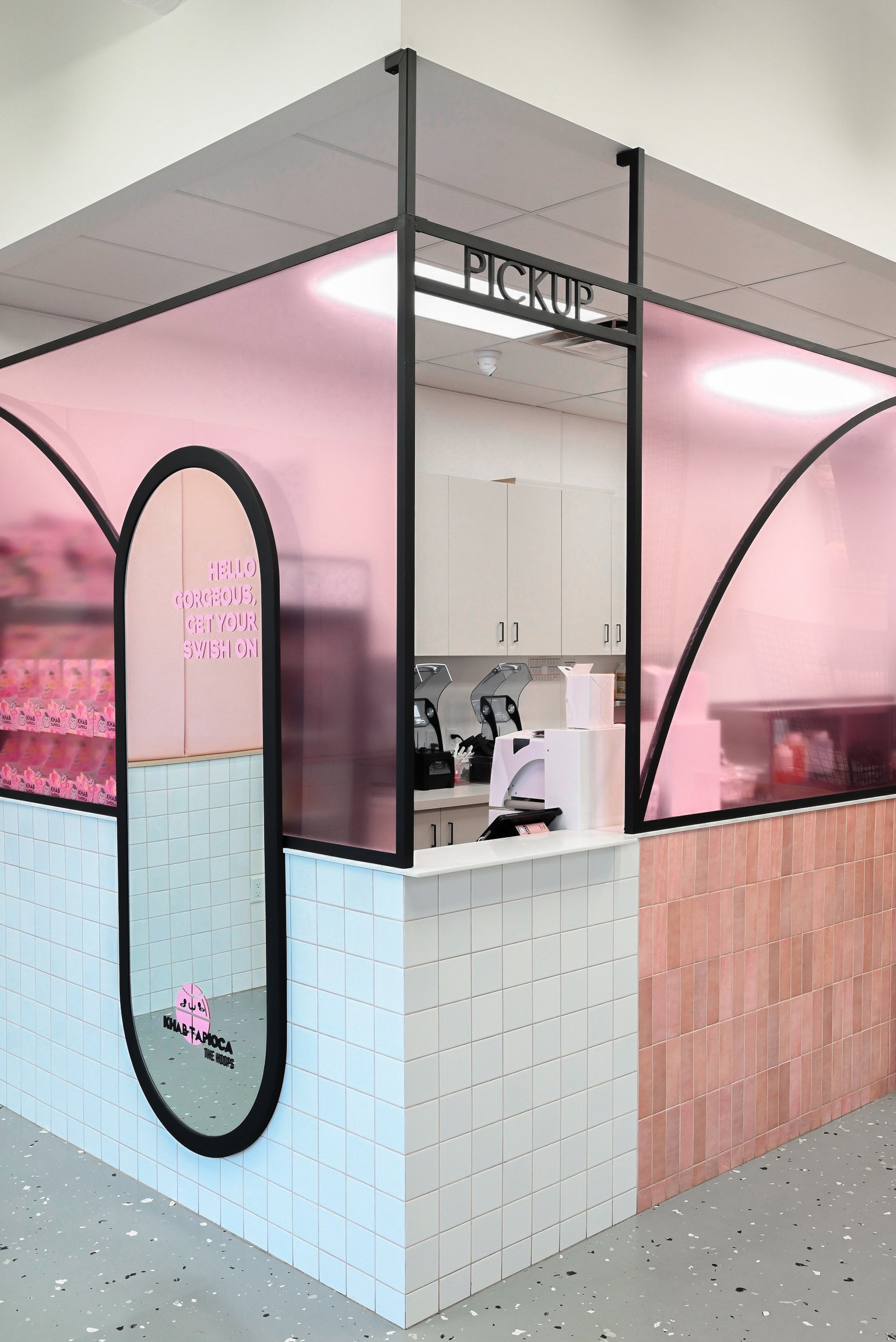 This bubble tea shop blends bold design with playful charm using curved black frames that mimic basketball court lines, soft pink and white tile, and a full-length mirror that adds depth and personality. A vibrant mix of sport and sweetness brought to life in a compact, curated space.