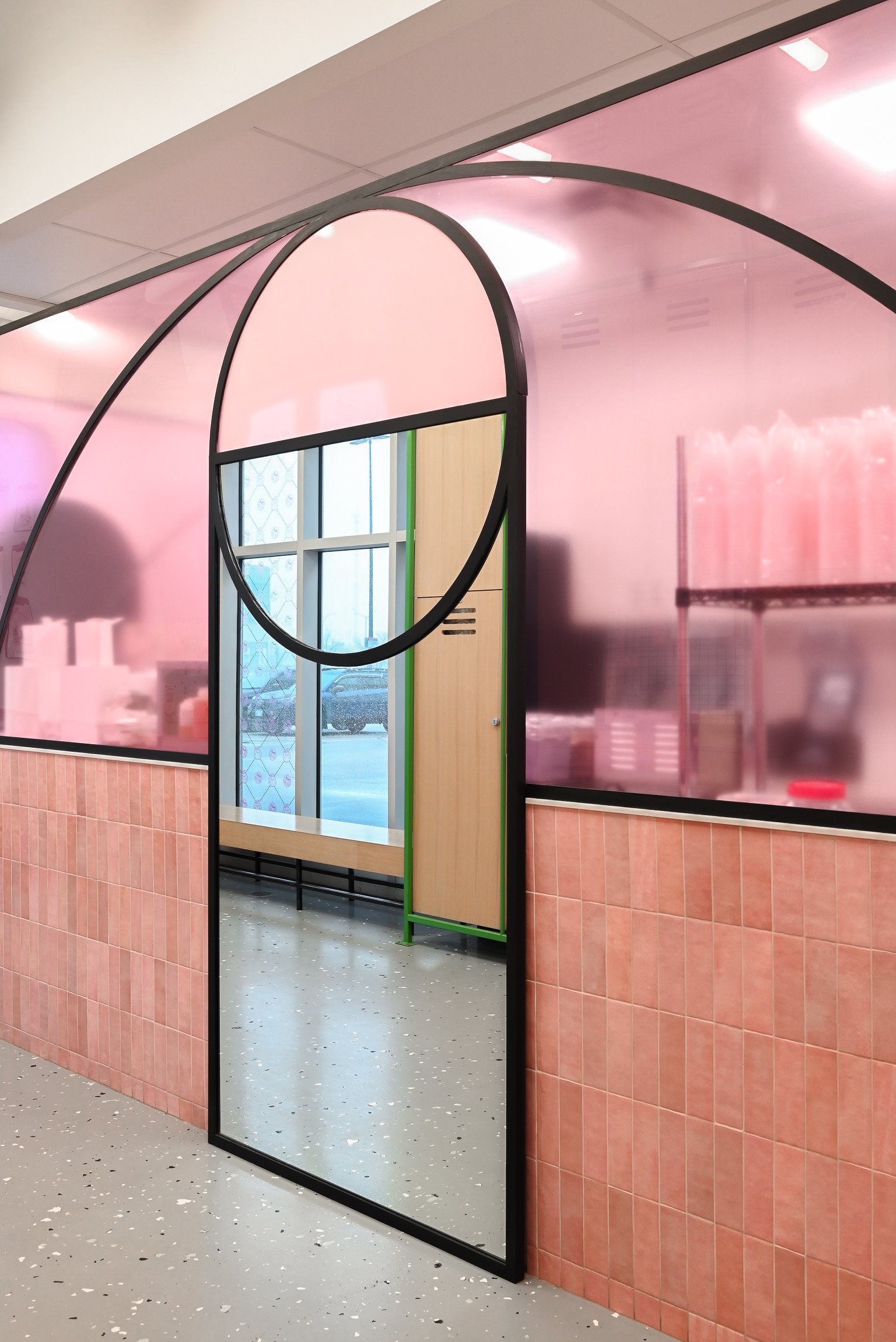 This bubble tea shop blends bold design with playful charm using curved black frames that mimic basketball court lines, soft pink tile, and a full-length mirror that adds depth and personality. A vibrant mix of sport and sweetness brought to life in a compact, curated space.