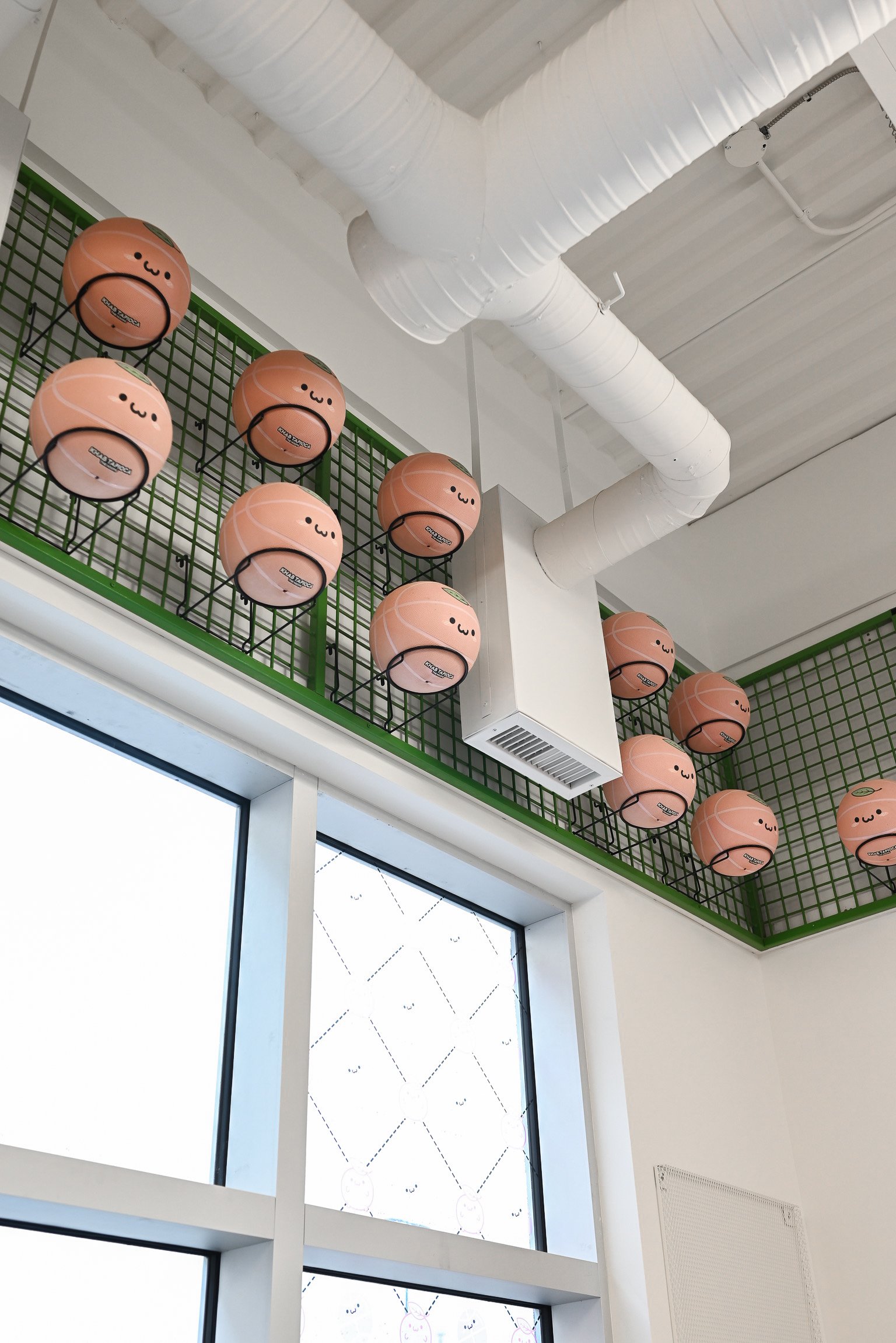 These kawaii-faced basketballs lining the upper walls add a whimsical, standout feature to the space. Their playful expressions and soft peach color make them feel more like mascots than sports equipment, perfectly capturing the fun, sporty branding of this basketball-inspired bubble tea shop.