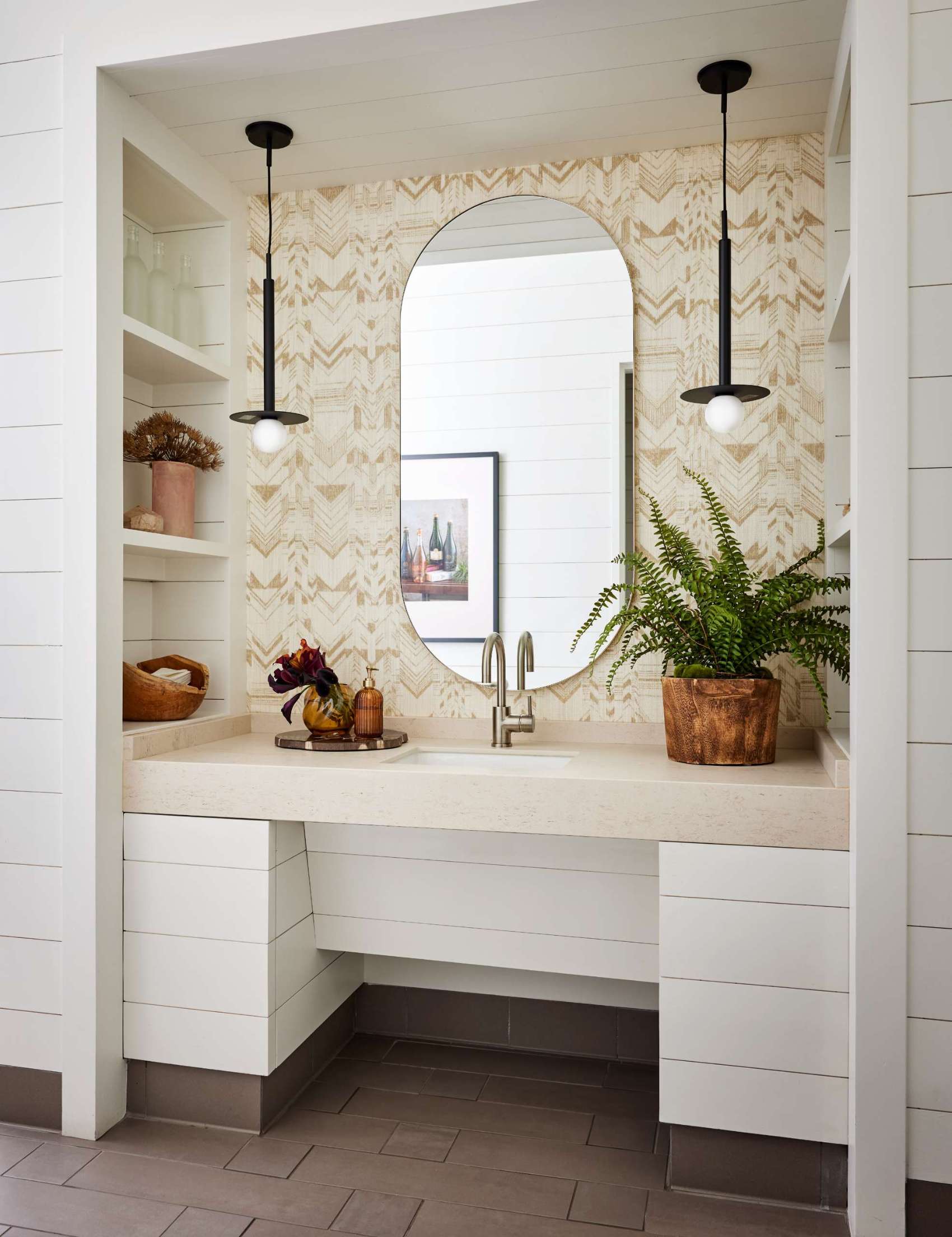 This bathrooms feature grass-like wallpaper, small plants, and dried floral arrangements, extending the calm, nature-inspired feeling throughout the space.