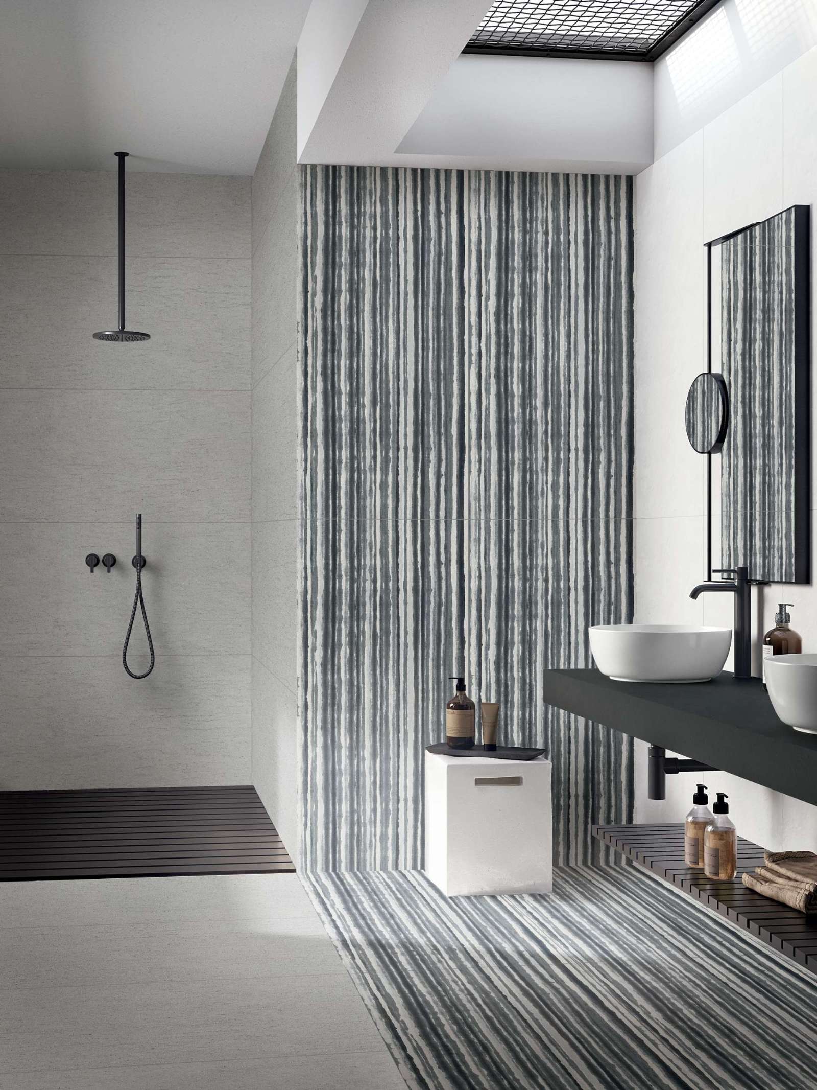 Vertical brushstroke stripes in cool-toned tile bring rhythm and calm to this skylit bathroom. A seamless flow from wall to floor adds a spa-like touch to the pared-back, monochrome design.