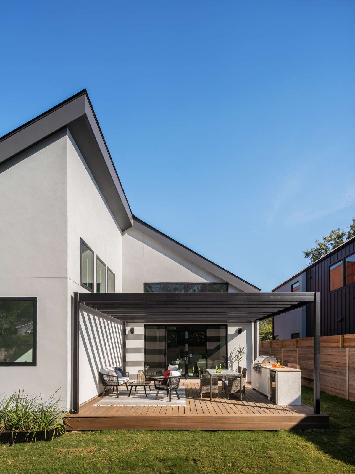 Just off the living room, a spacious deck extends the living area outdoors. Clad in smooth wood planks and framed by a minimalist pergola, the space feels warm yet modern. An outdoor kitchen adds function, making it ideal for hosting or quiet evening meals under the open sky.