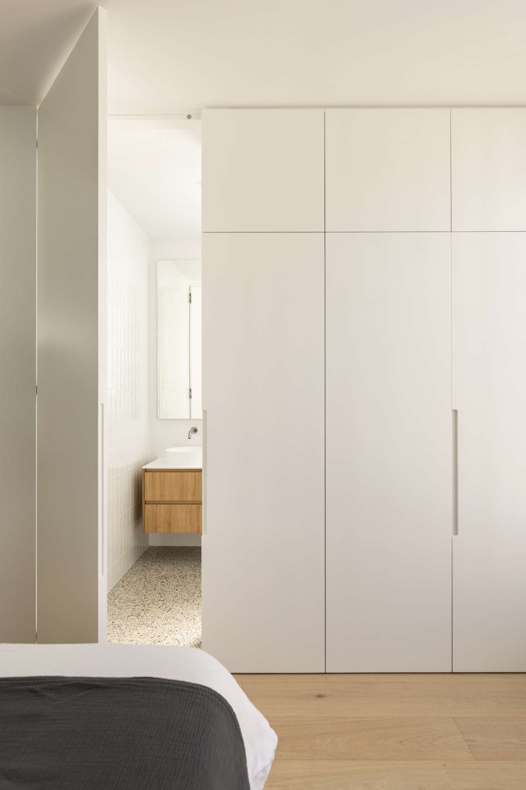 The new primary bedroom ensuite, now concealed behind a closet door, continues the home’s sculptural language with a soft, curving shower wall that adds an unexpected moment of architectural elegance.