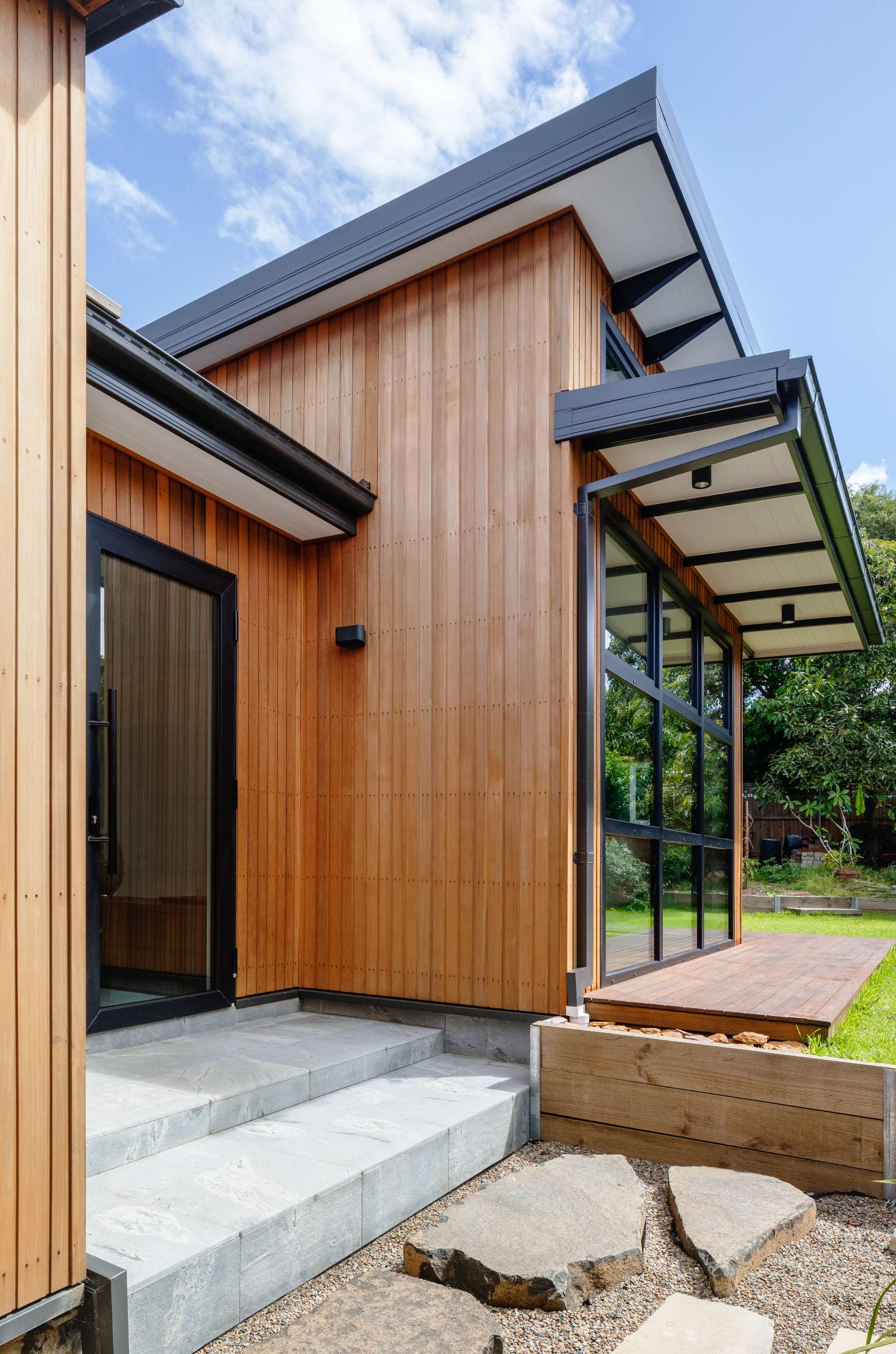 The front entry unfolds like a quiet welcome, with textured stone steps and delicate shoji-style glazing nodding to traditional Japanese thresholds.