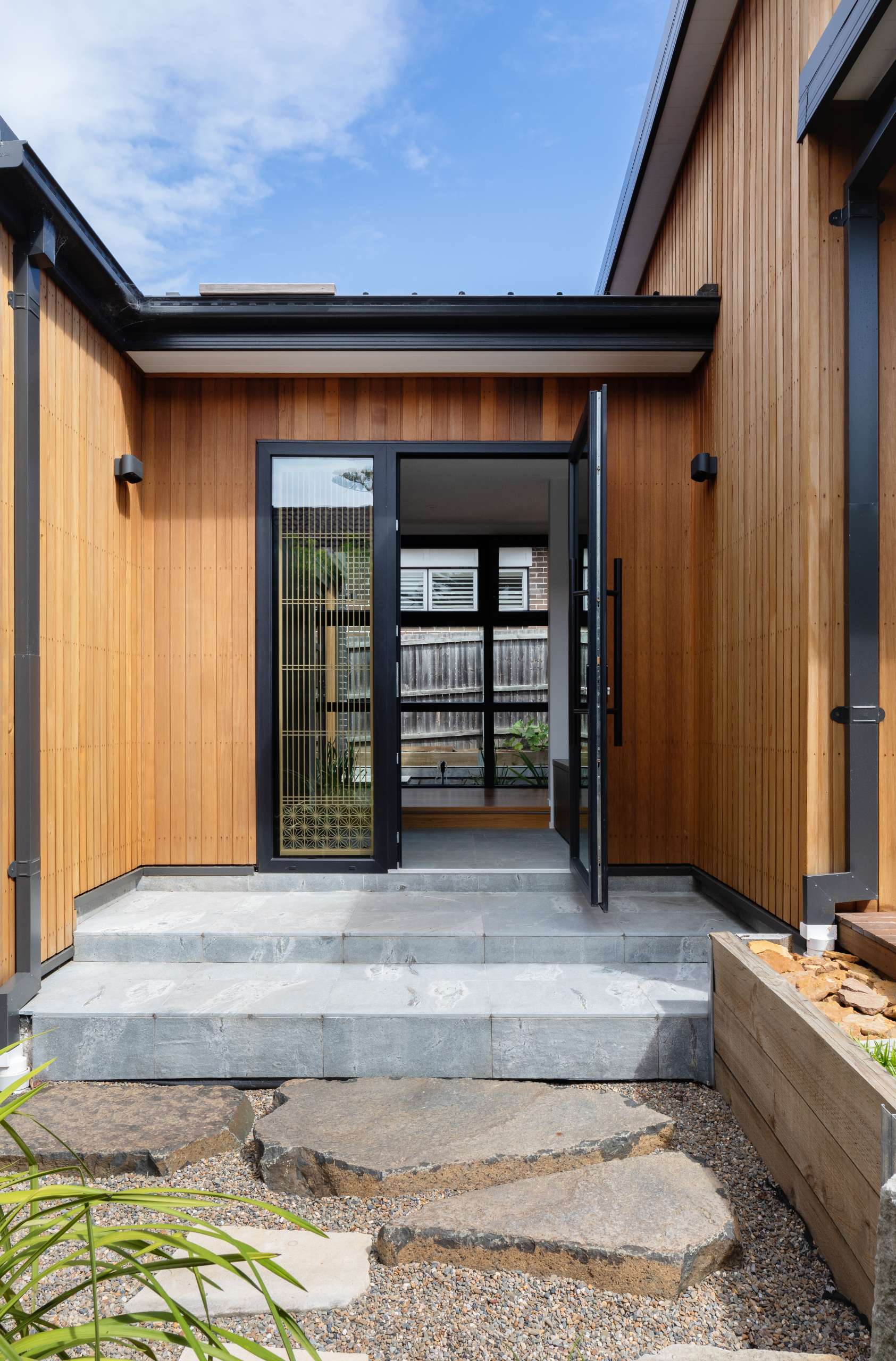Every detail of this extension celebrates simplicity, from the clean architectural lines to the layered stone and gravel path leading to the door.
