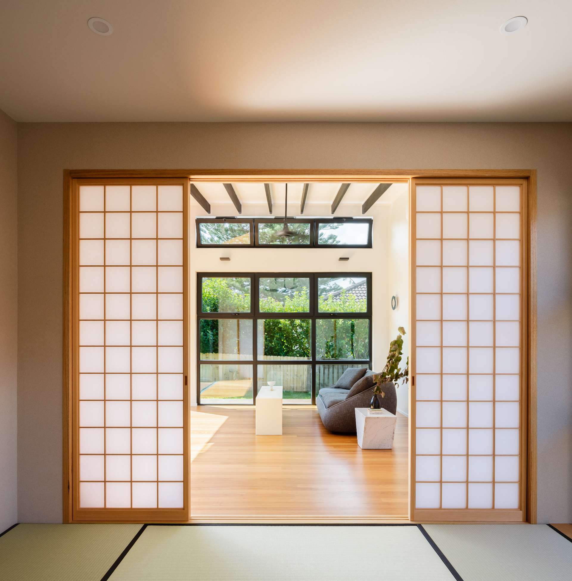 A serene fusion of traditional and modern, tatami flooring and shoji screens frame a sunlit room.