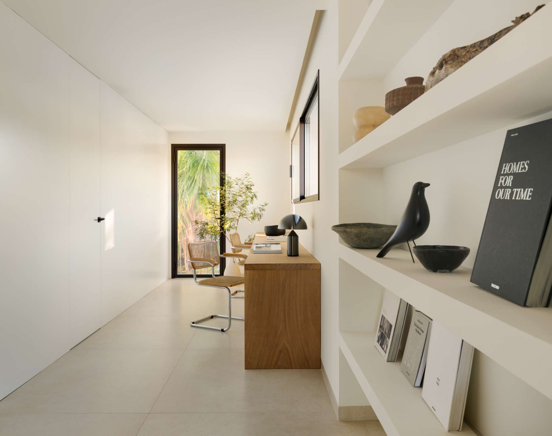 A serene home office designed for focus without rigidity. Natural light bathes the space, highlighting the clean lines of wood desk setup for two. Woven chairs, a leafy plant, and minimal decor reinforce the balance between functionality and calm.