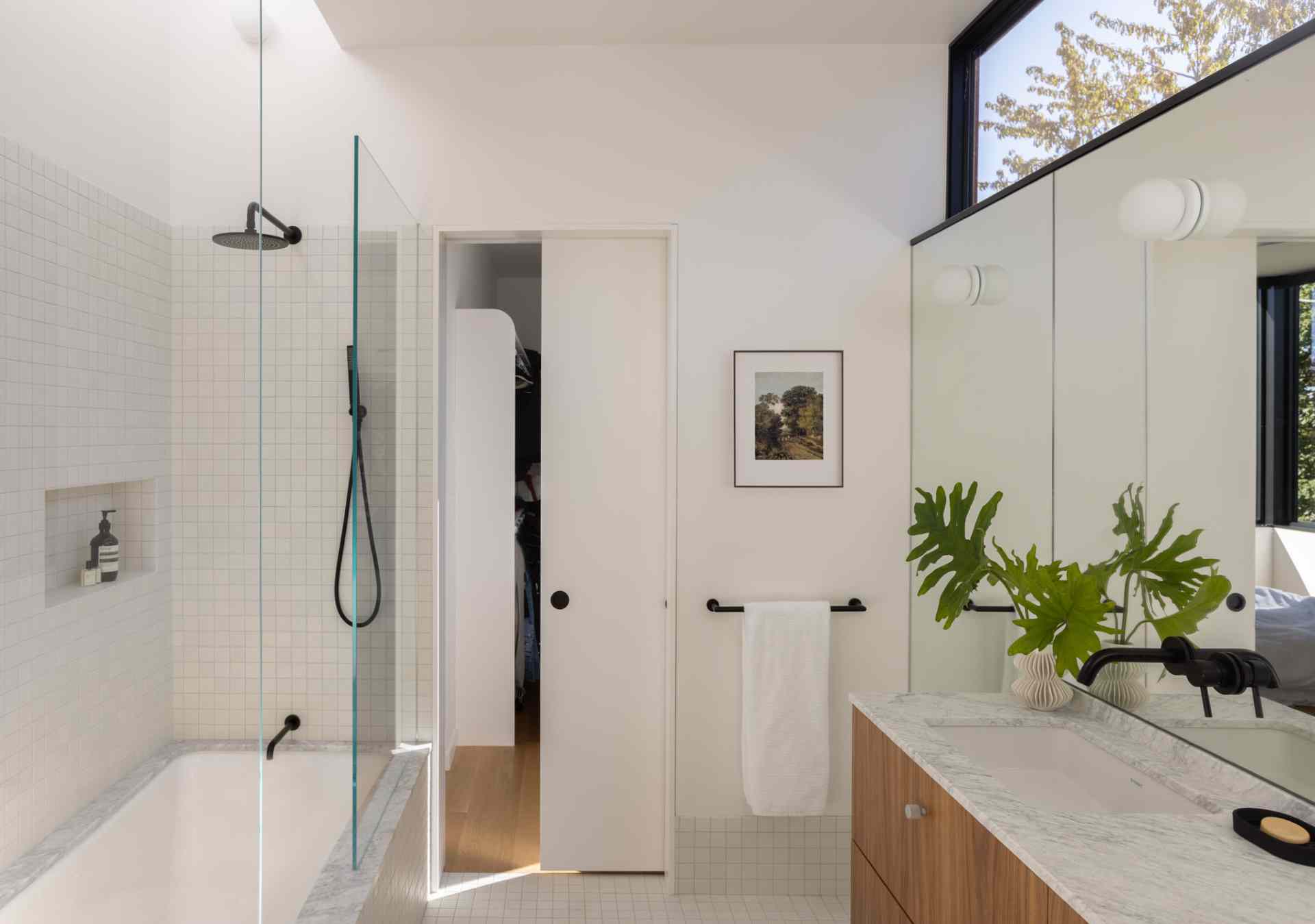Modern white bathroom with wood and black accents.