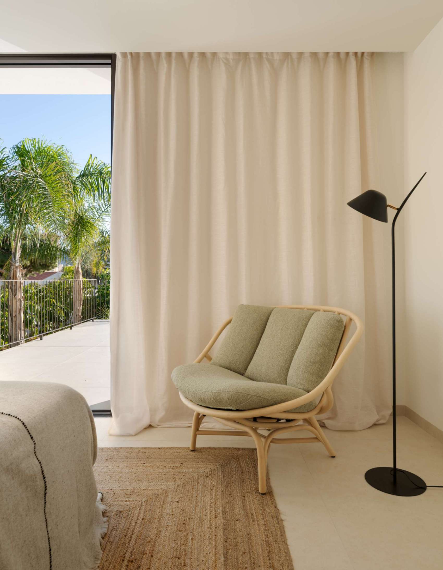 The design of this bedroom is an exercise in restful restraint. Sunlight filters through sliding doors that open onto a balcony surrounded by lush greenery, while soft linen bedding, natural textures, and minimal styling keep the mood grounded. A timber feature wall adds quiet warmth, and sculptural accents, from side tables to abstract art, offer subtle personality within the calm palette. It’s a room designed for retreat, where every element supports peace.