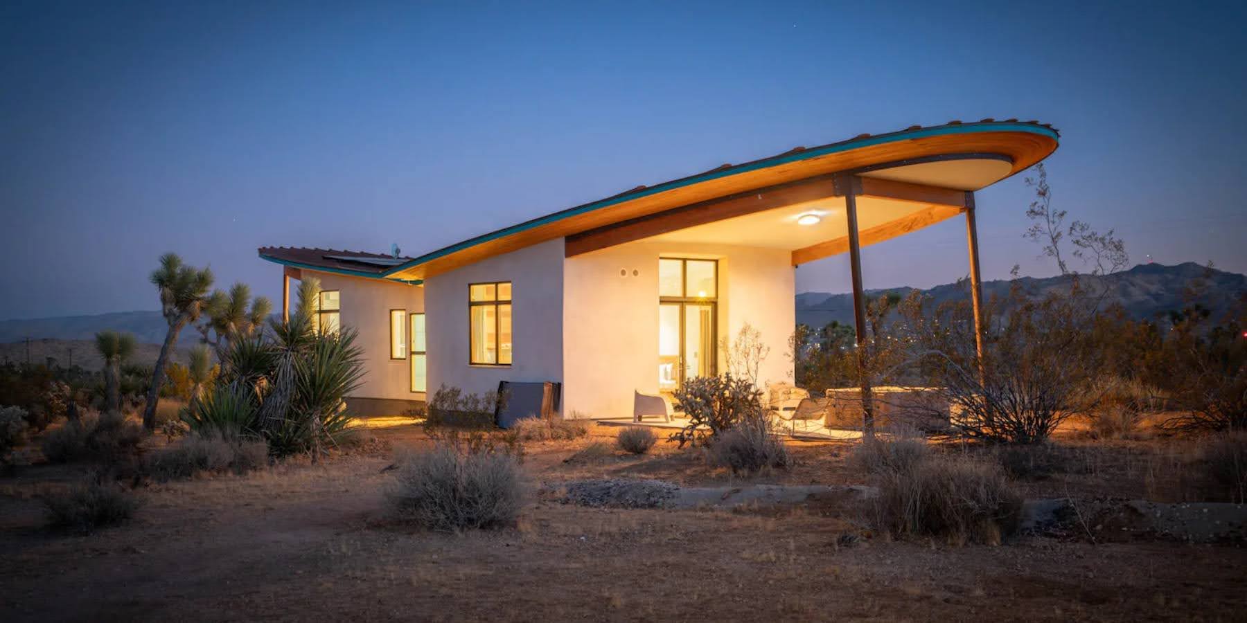 A radical strawbale cabin in the desert, has a butterfly roof and is covered in a natural lime plaster.