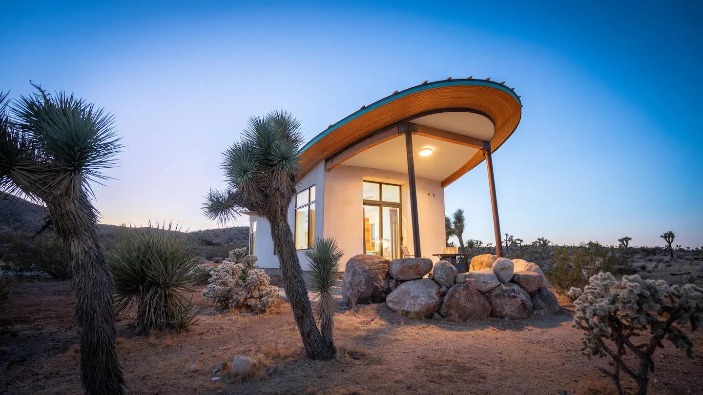 A radical strawbale cabin in the desert, has a butterfly roof and is covered in a natural lime plaster.