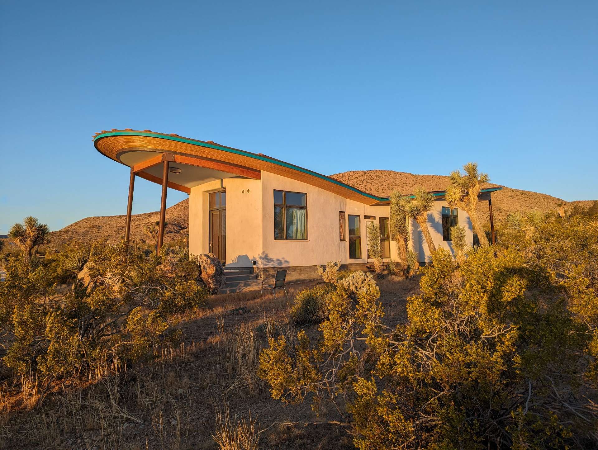 A radical strawbale cabin in the desert, has a butterfly roof and is covered in a natural lime plaster.