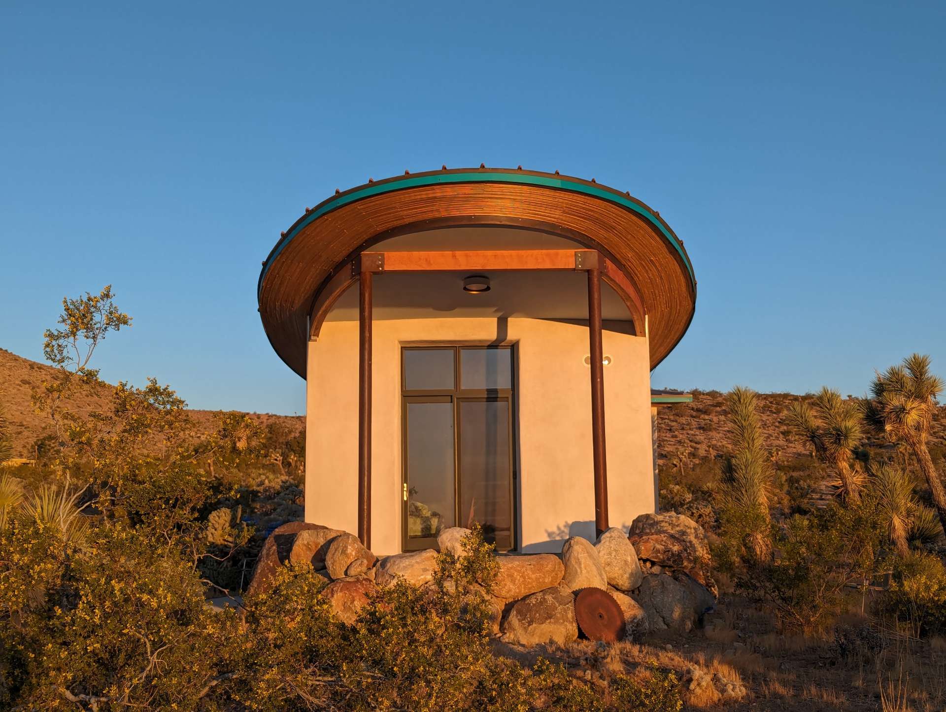 A radical strawbale cabin in the desert, has a butterfly roof and is covered in a natural lime plaster.