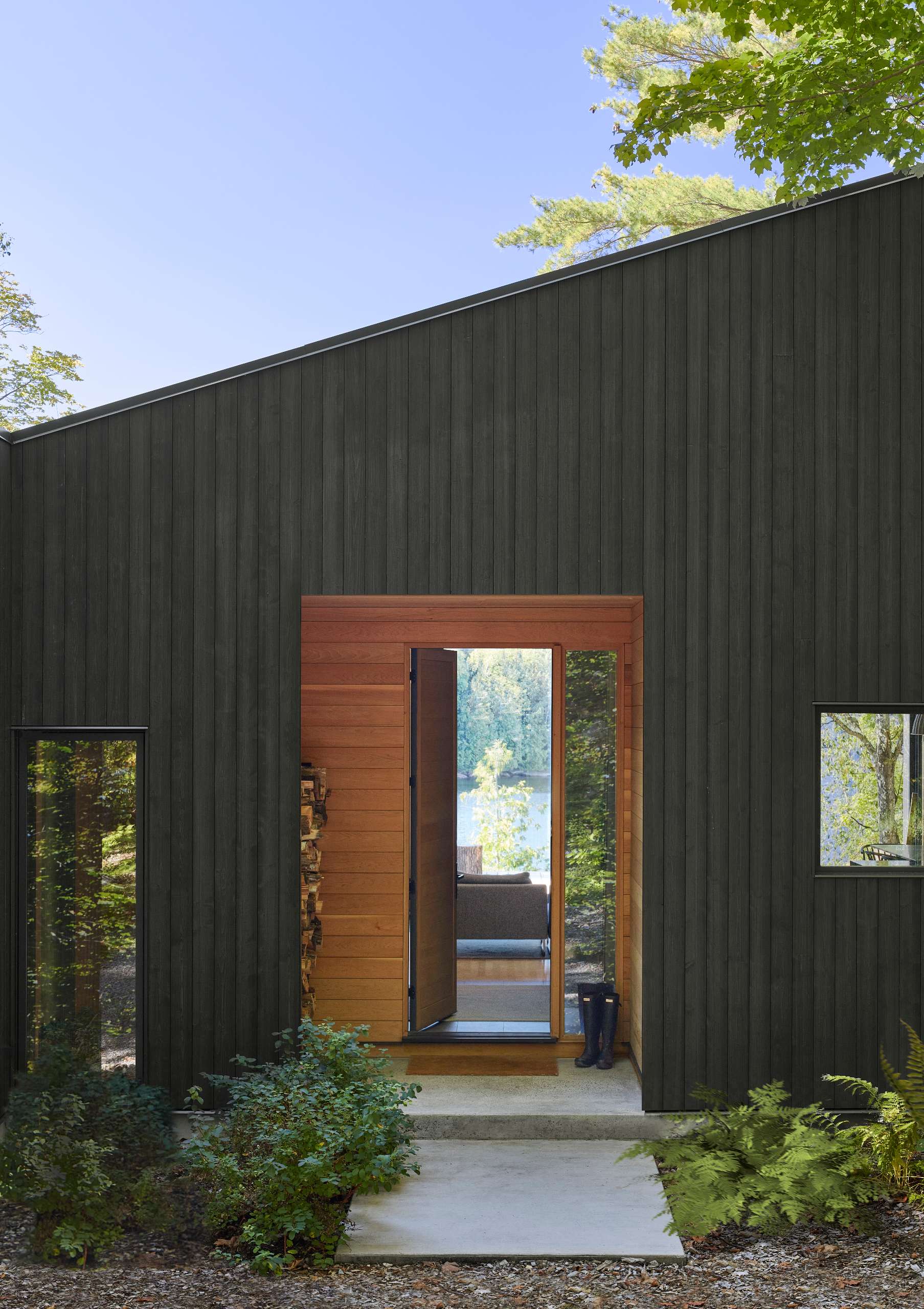 Upon entry to this modern cottage, visitors are immediately greeted with a view through the living space and out the large rear sliding glass doors, revealing the lake beyond.