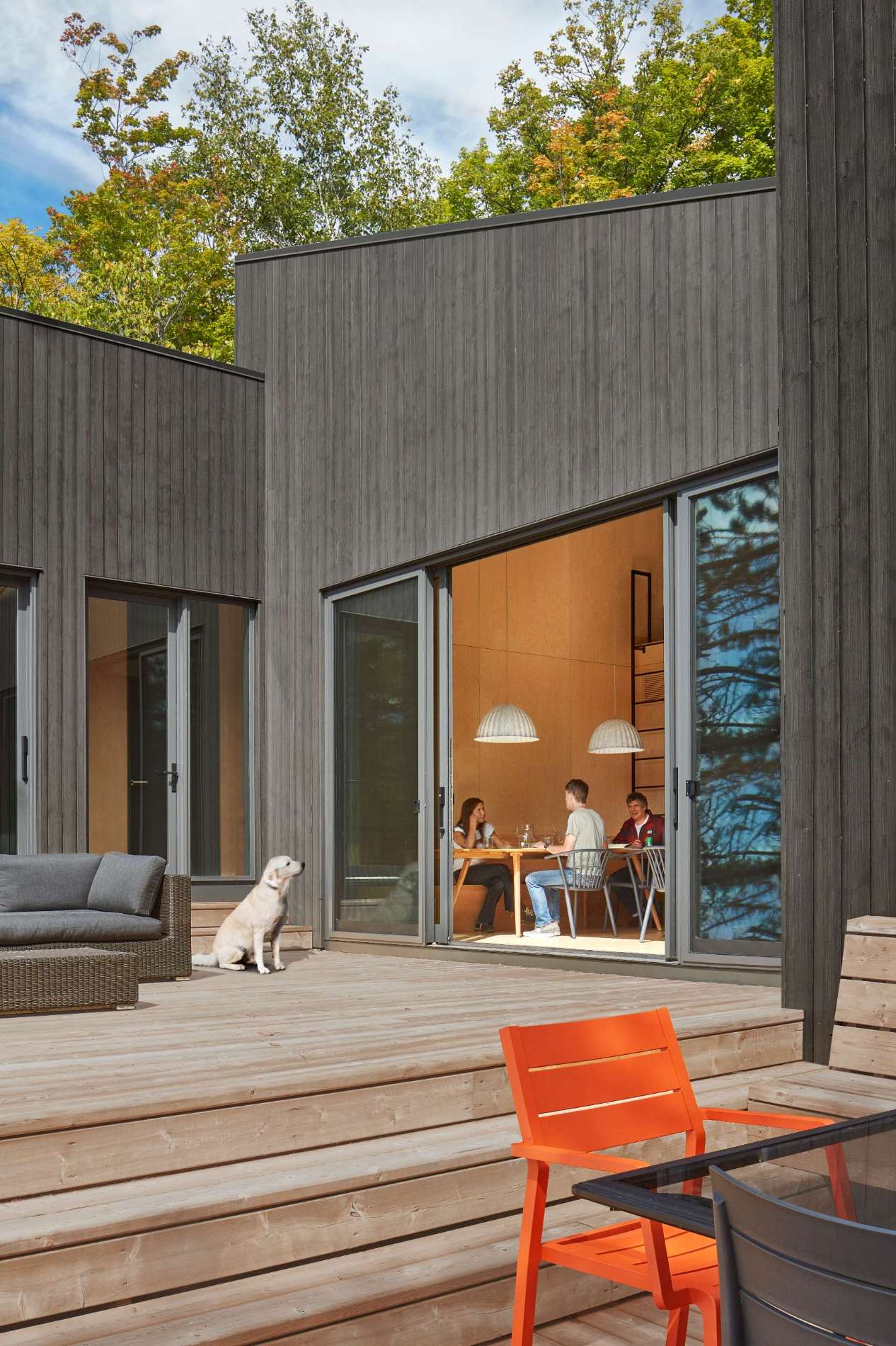 An expansive deck spans multiple levels, bridging the sloped site's grade differences and cascading down in multiple tiers towards the water's edge.