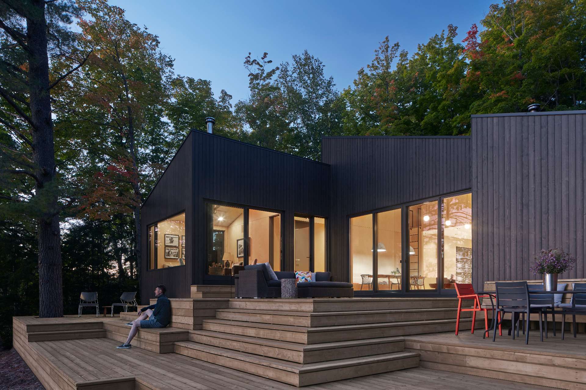 An expansive deck spans multiple levels, bridging the sloped site's grade differences and cascading down in multiple tiers towards the water's edge.