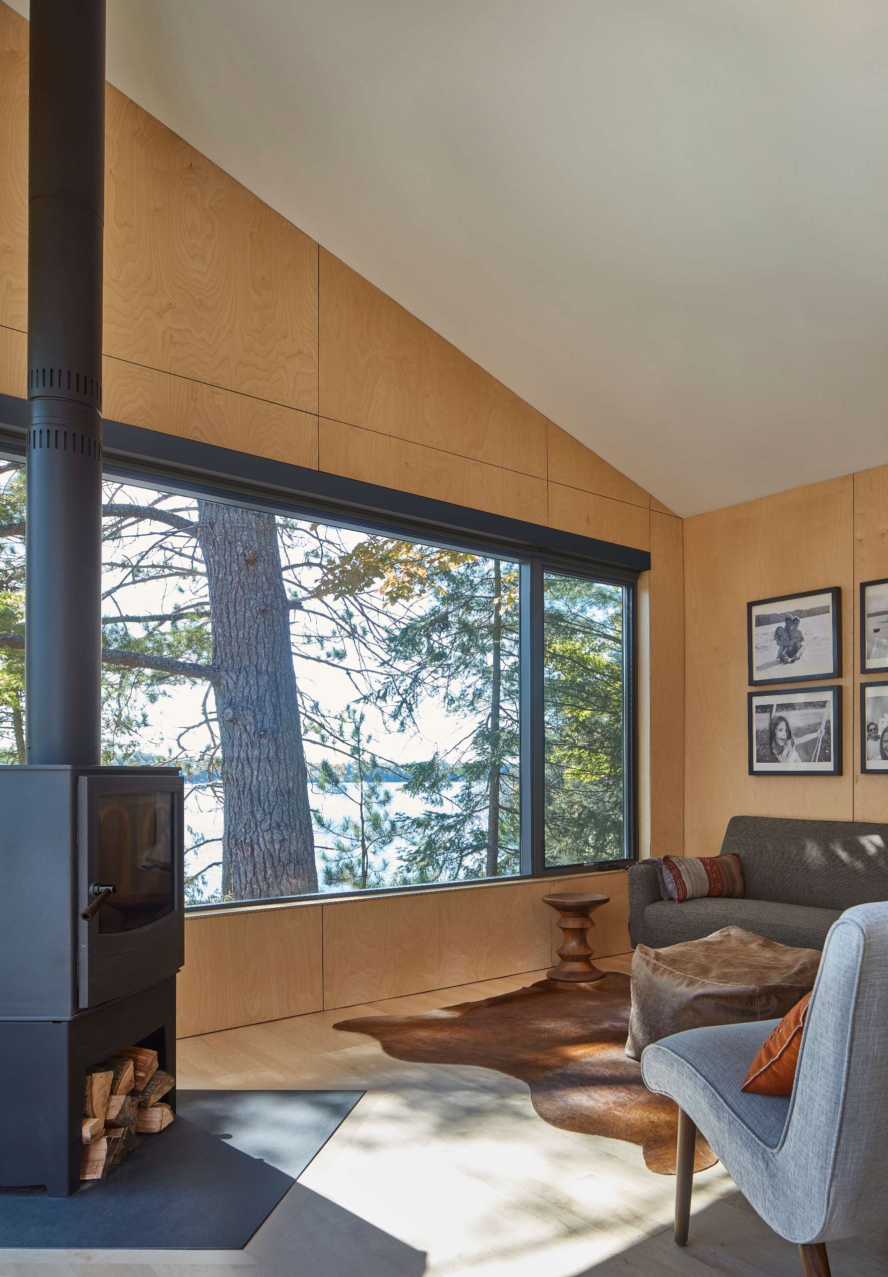 The cold-rolled steel behind the fireplace in this living room creates a striking contrast to the maple plywood-lined walls, adding visual interest and texture to the space.