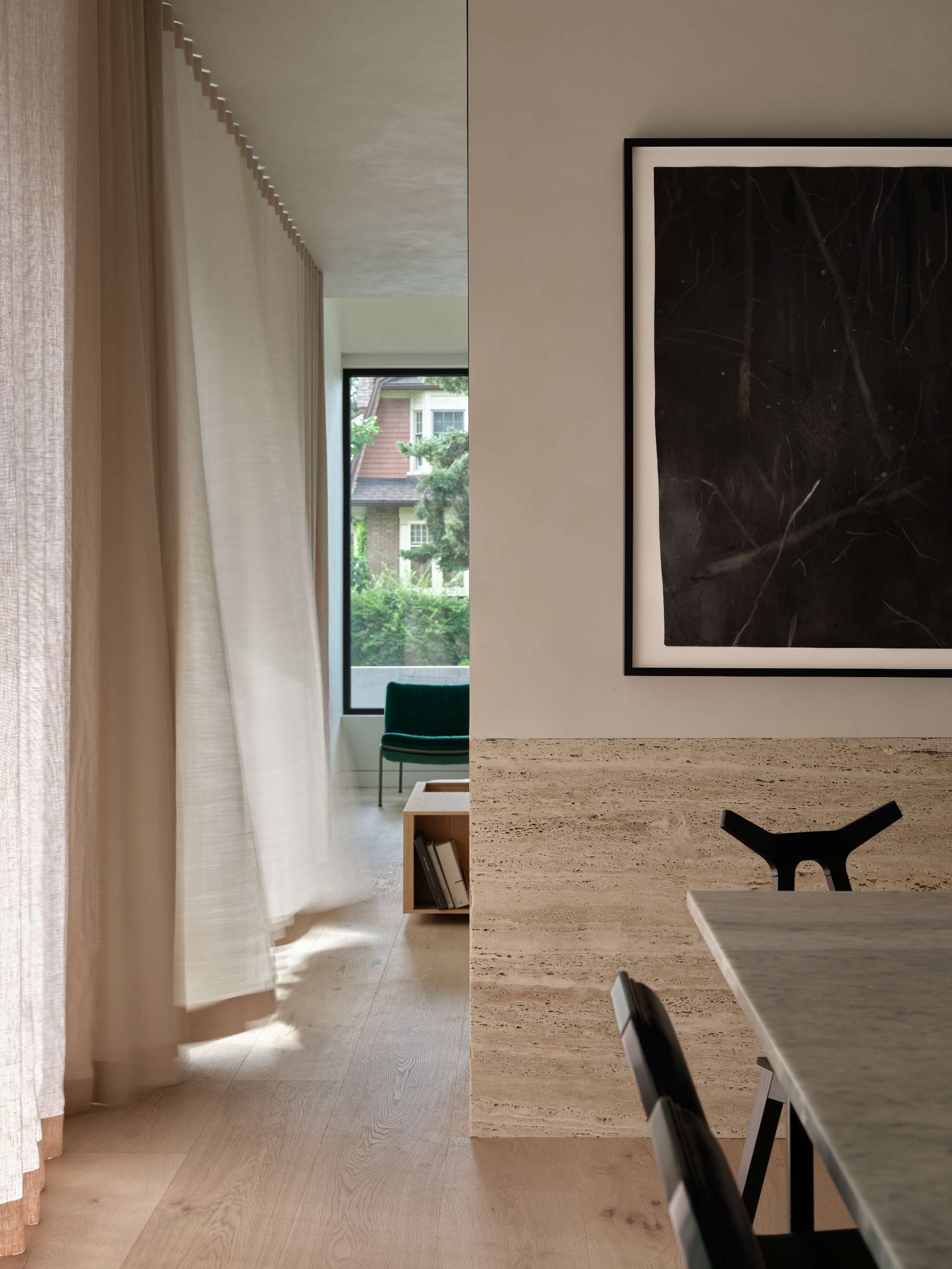 Anchored by a stone table and surrounded by black dining chairs, this dining room balances weight and lightness.