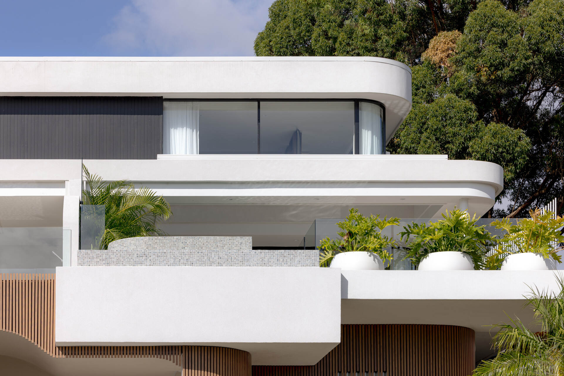 A modern home with wood details and curves on the facade.