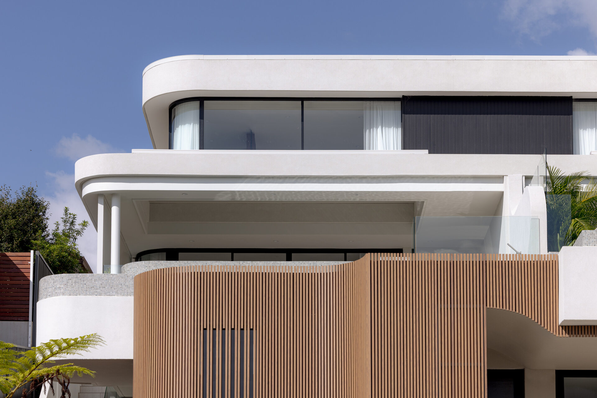A modern home with wood details and curves on the facade.