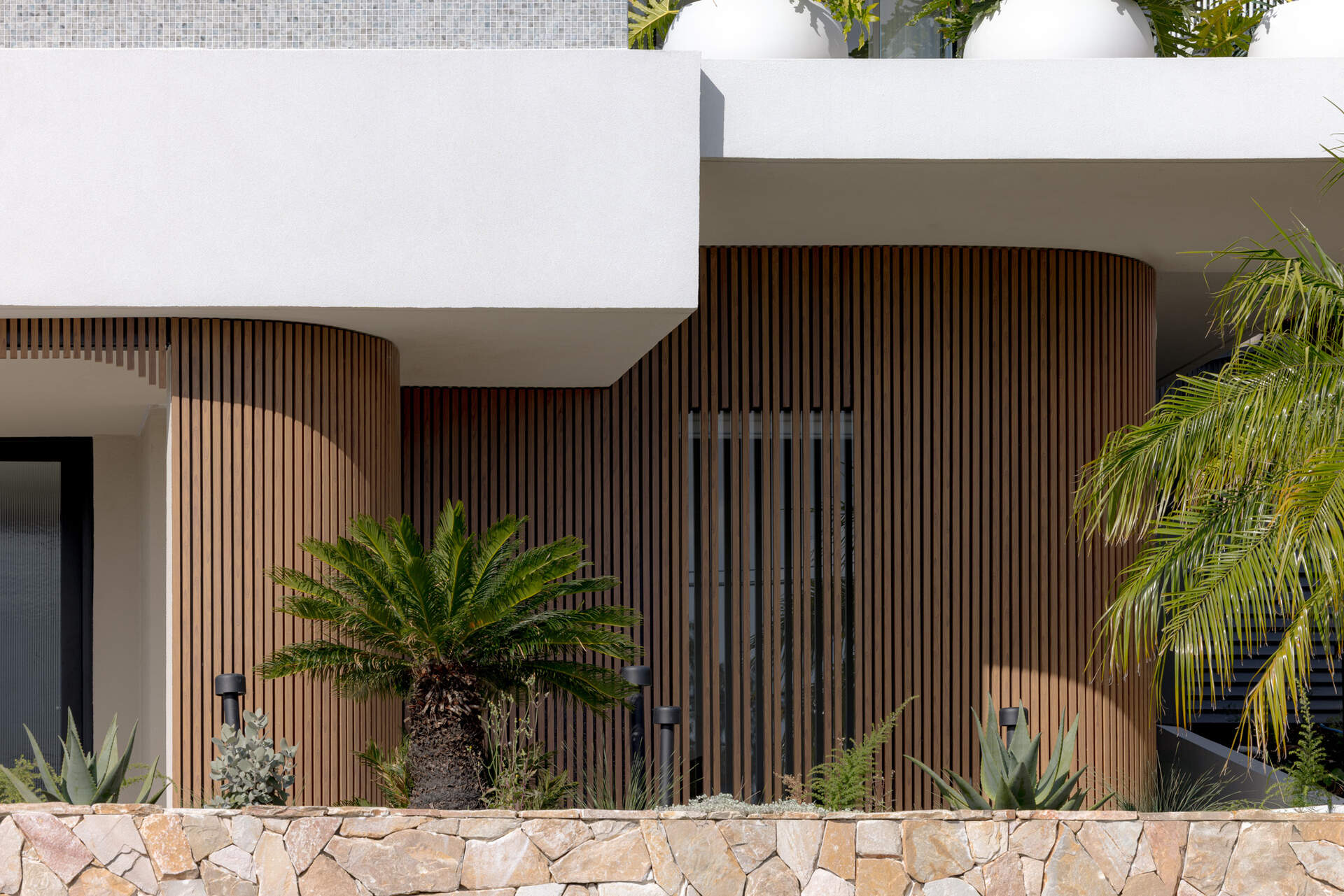 A modern home with wood details and curves on the facade.