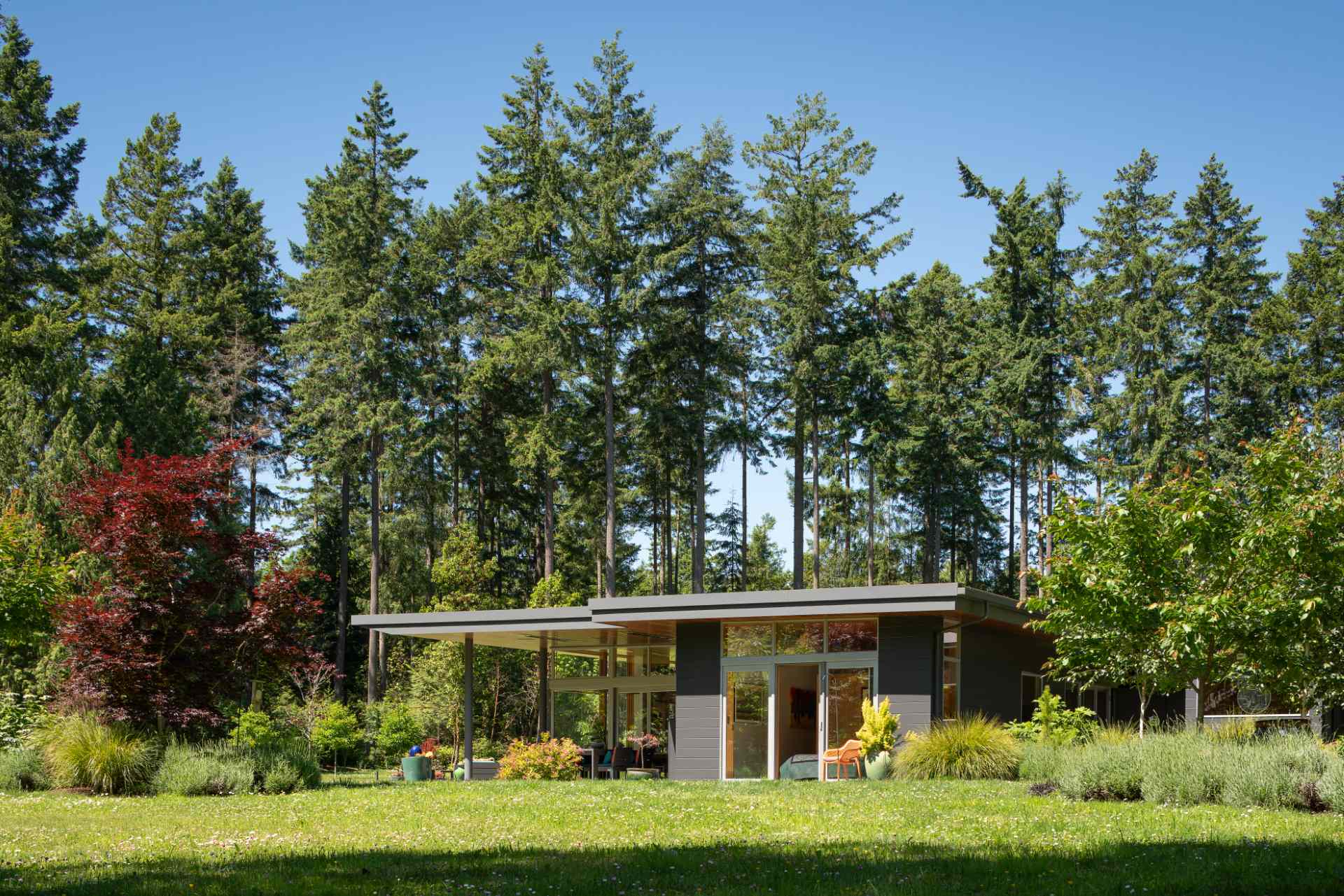 A single tapered roof ties together this home, carriage house, and sauna creating a generous covered entry promenade.