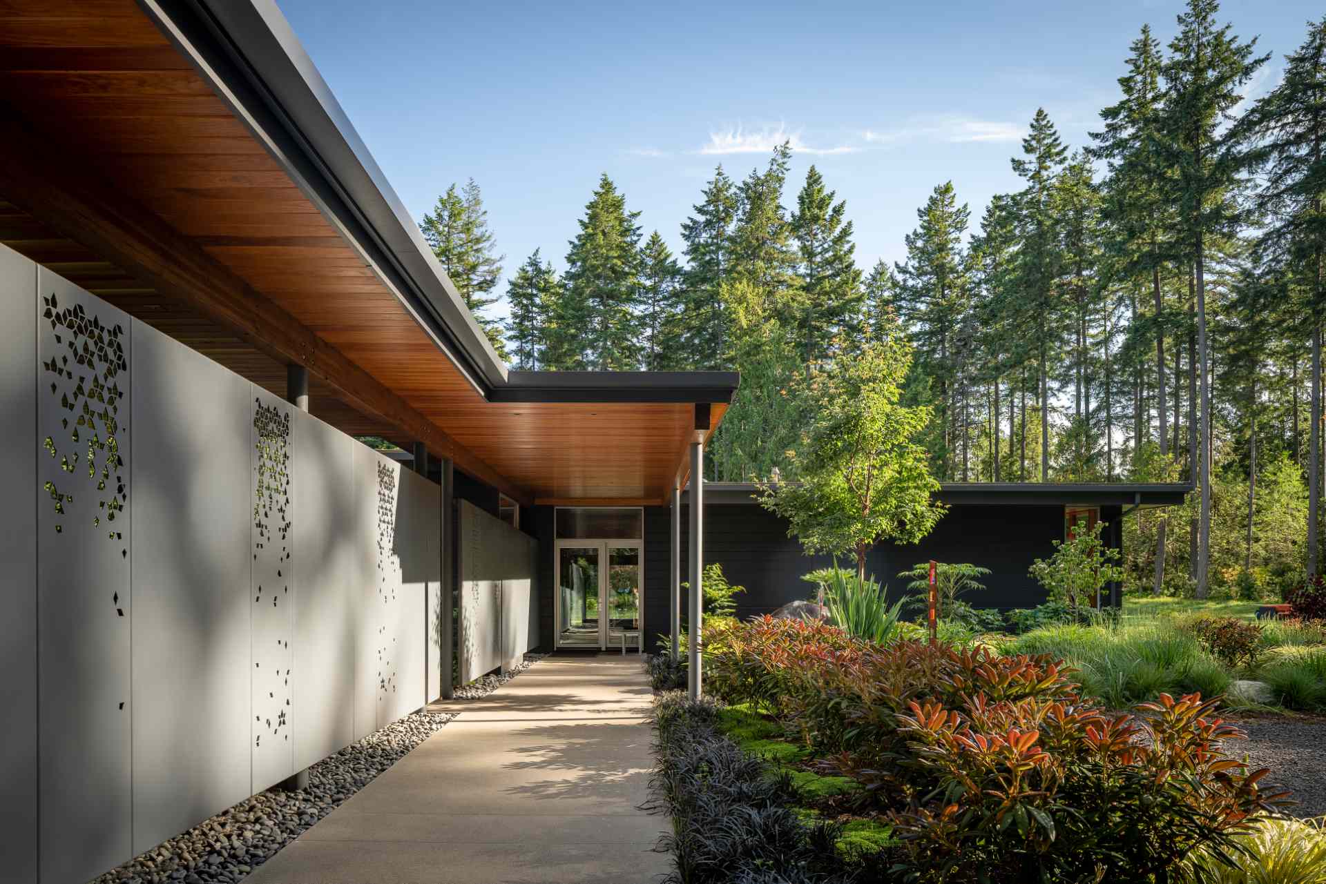 The entry walk, which is defined by a series of water jet cut metal panels, creates a private interior court for the outdoor shower and sauna.