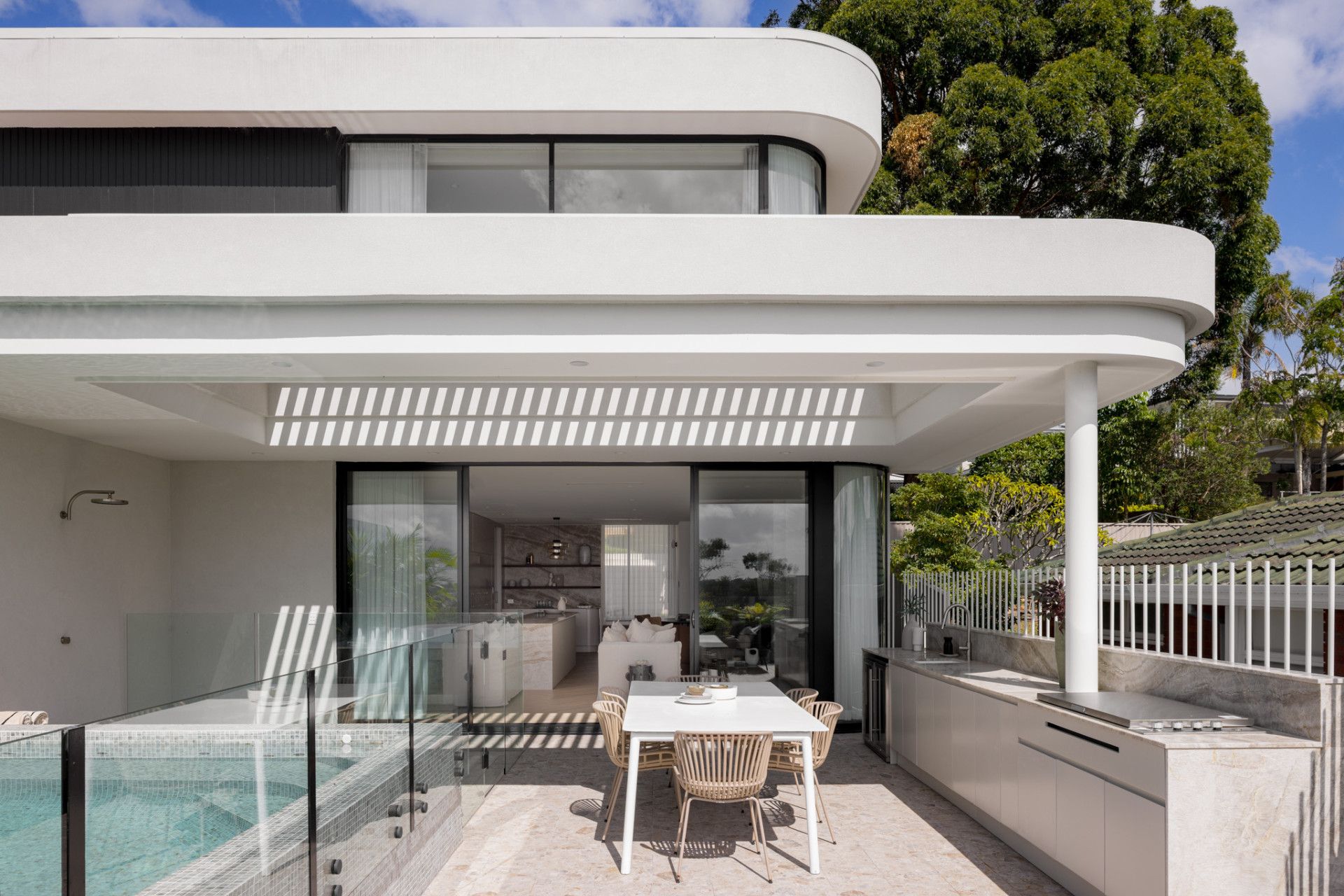 The living room and kitchen open to the outdoor space, where there's a bbq area, outdoor dining, and a swimming pool.