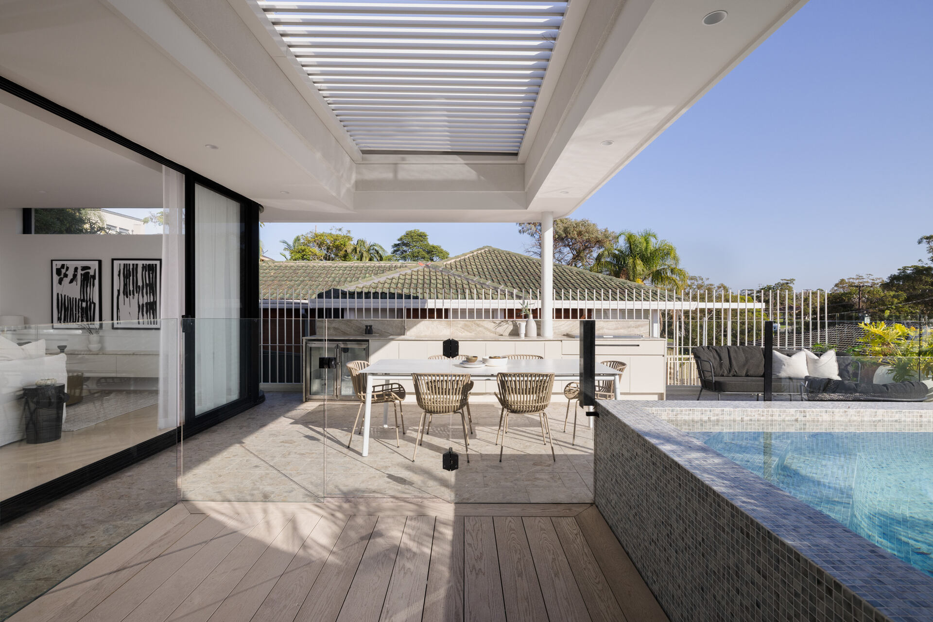 The living room and kitchen open to the outdoor space, where there's a bbq area, outdoor dining, and a swimming pool.