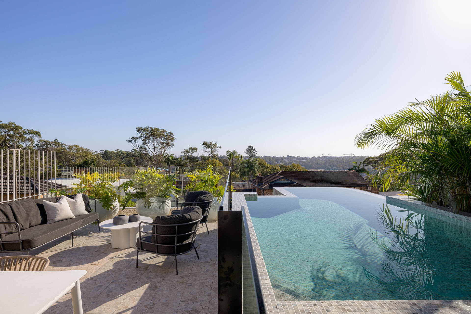The living room and kitchen open to the outdoor space, where there's a bbq area, outdoor dining, and a swimming pool.