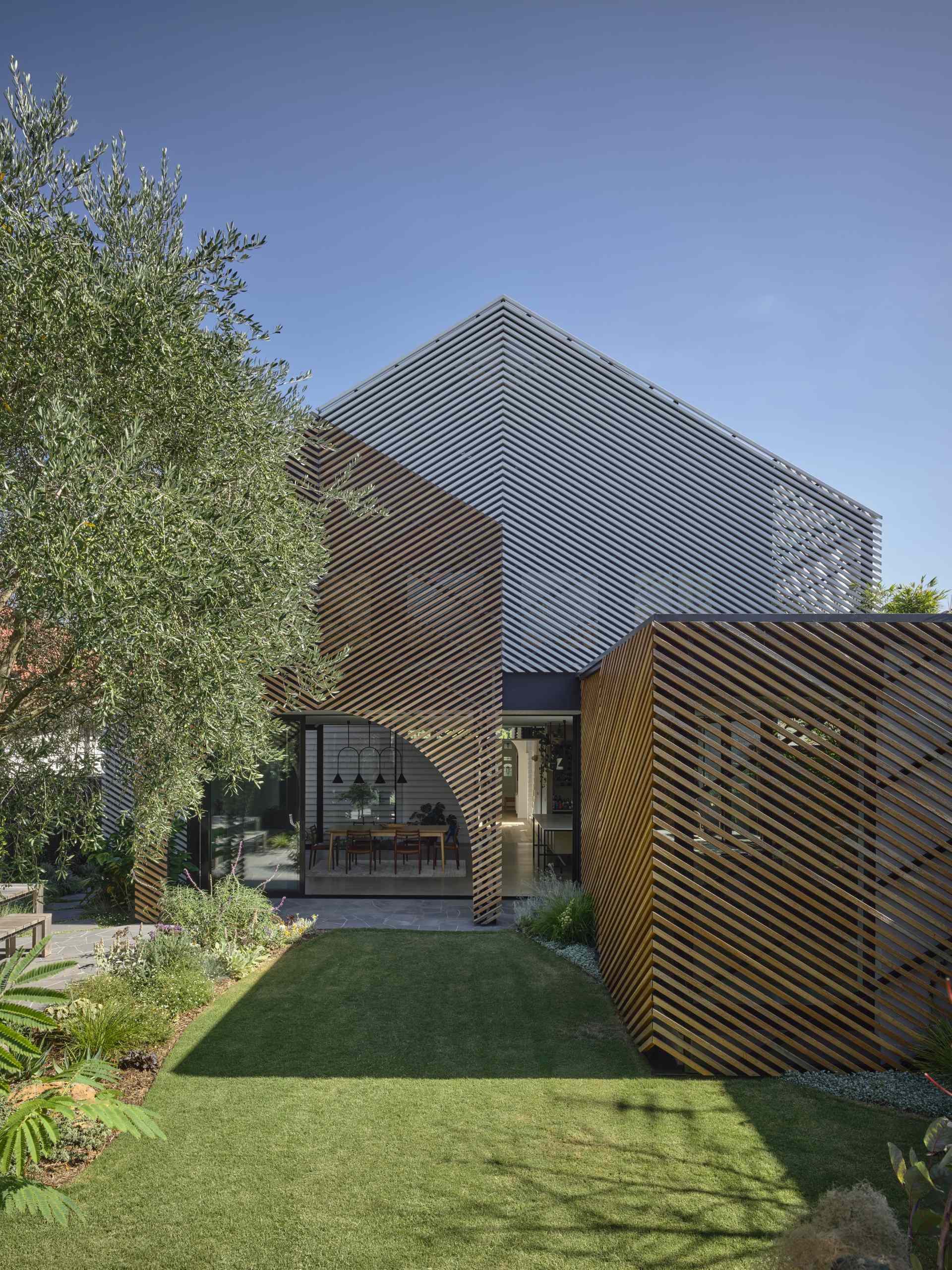 A batten screen was used to unify the rear extension with the original home, bringing together the addition in a simple meeting of forms, while providing shade and protection, restricting overlooking, and creating a covered verandah.