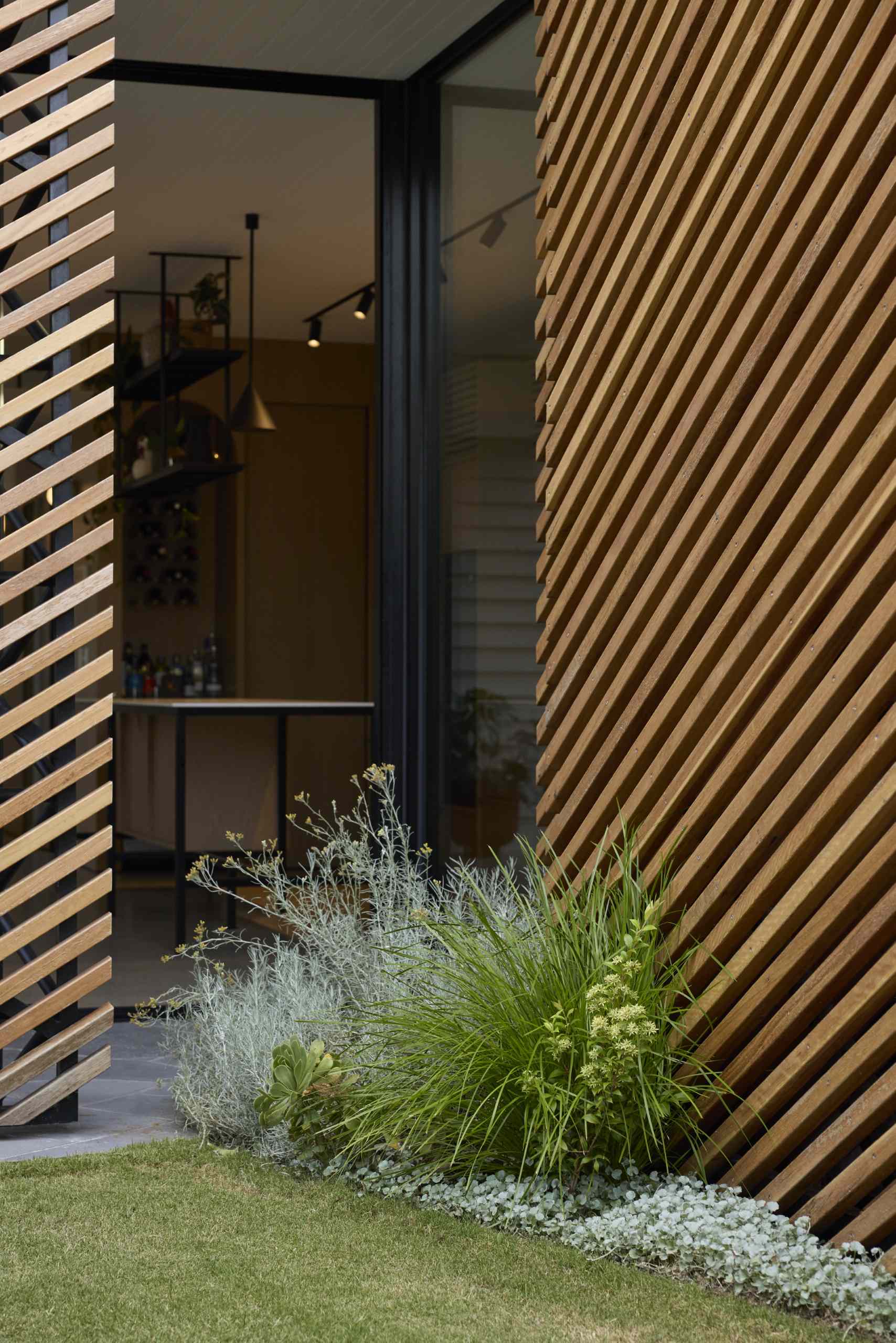 A batten screen was used to unify the rear extension with the original home, bringing together the addition in a simple meeting of forms, while providing shade and protection, restricting overlooking, and creating a covered verandah.