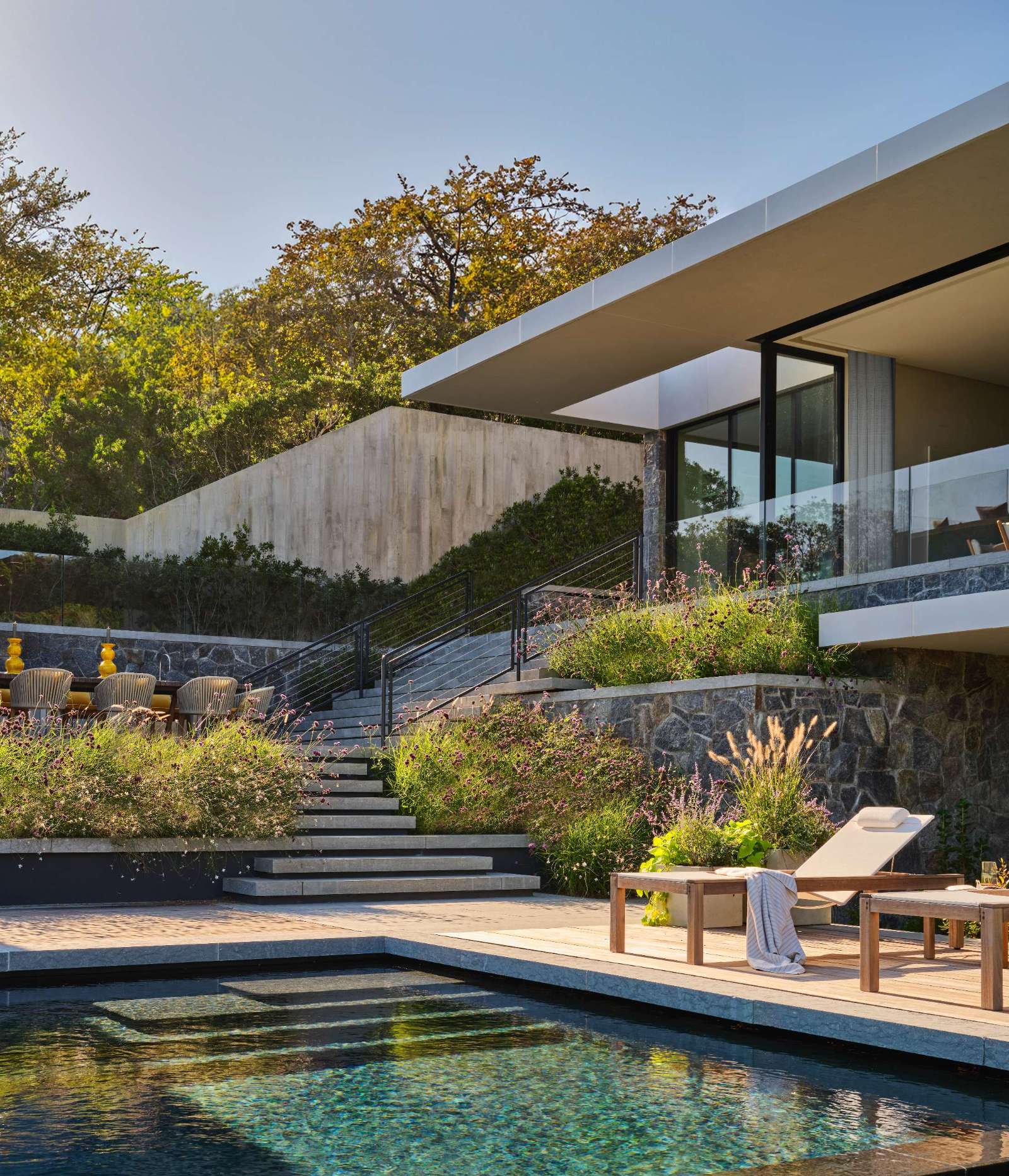 This modern home has three distinct levels to it, while outside, there's a terraced backyard with swimming pool, outdoor kitchen, and pool house.