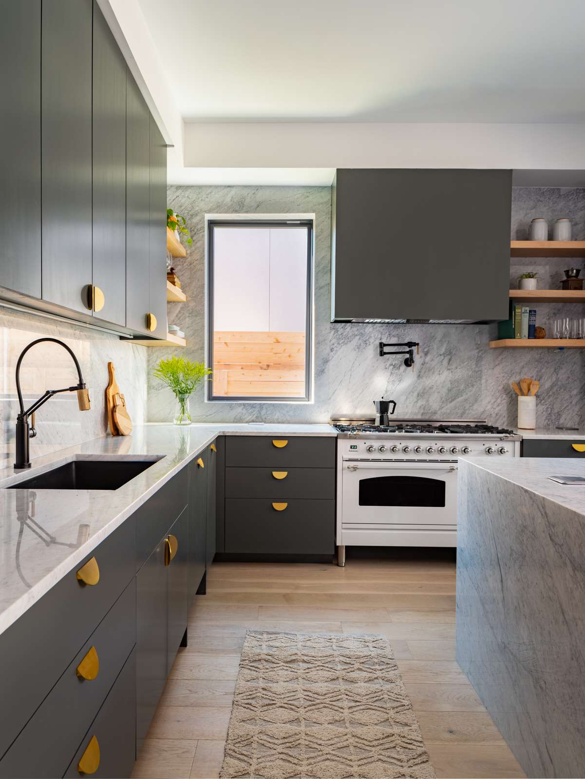The kitchen combines clean lines with inviting textures. Flat-panel dark cabinetry brings warmth to the space, while a sleek stone island provides contrast and utility. Integrated appliances and minimalist hardware keep the look streamlined, and under-cabinet lighting adds subtle depth.