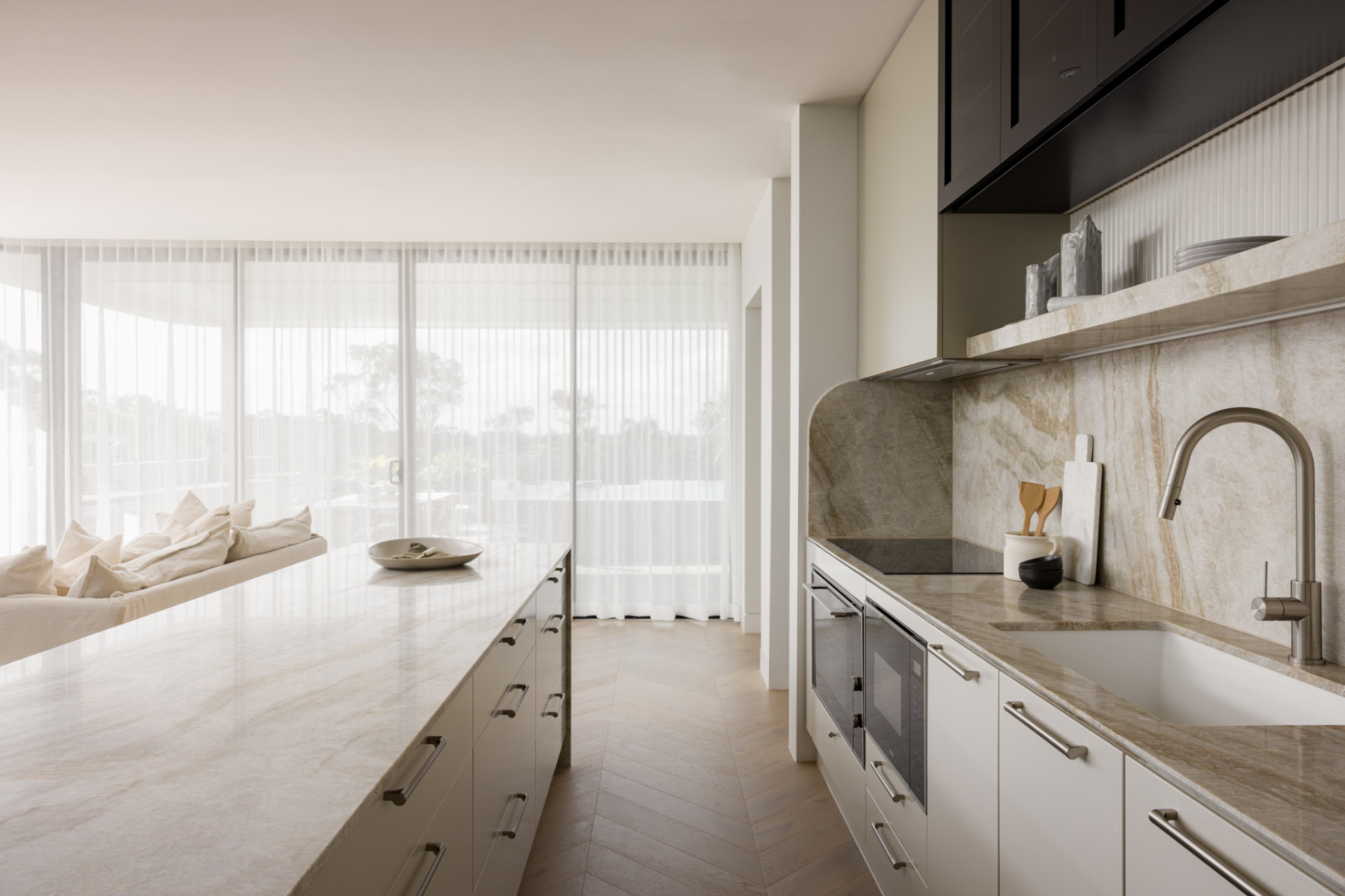 This modern kitchen has a large island with a fluted detail. The light and warm color tones chosen by the client to provide a tranquil and calming environment.