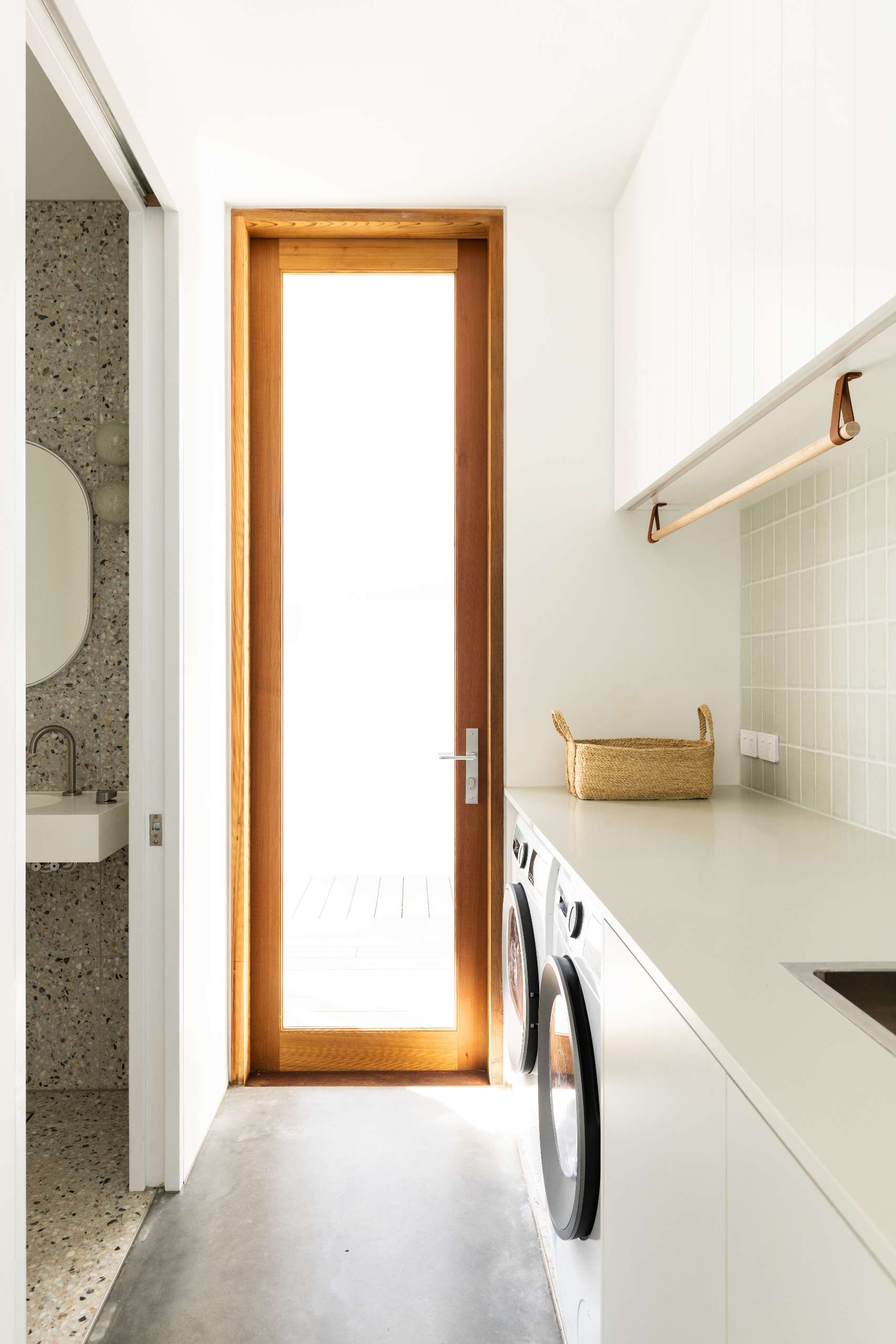 This laundry room with a powder room tucked behind a pocket door, stays invisible until needed, then fully functional when in use.