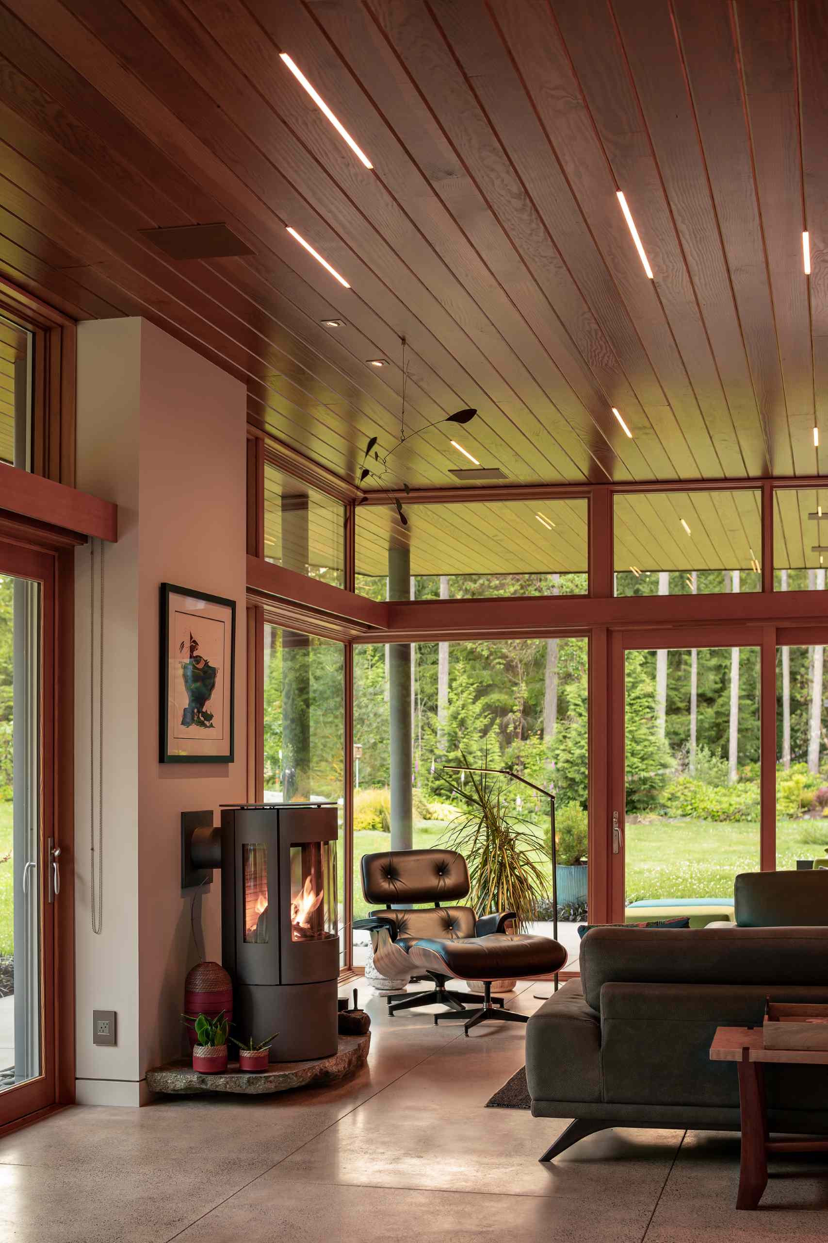 In this living room, natural light floods the interior, while a fireplace keeps things warm and custom-designed cabinetry hides the TV and a workspace when not in use.