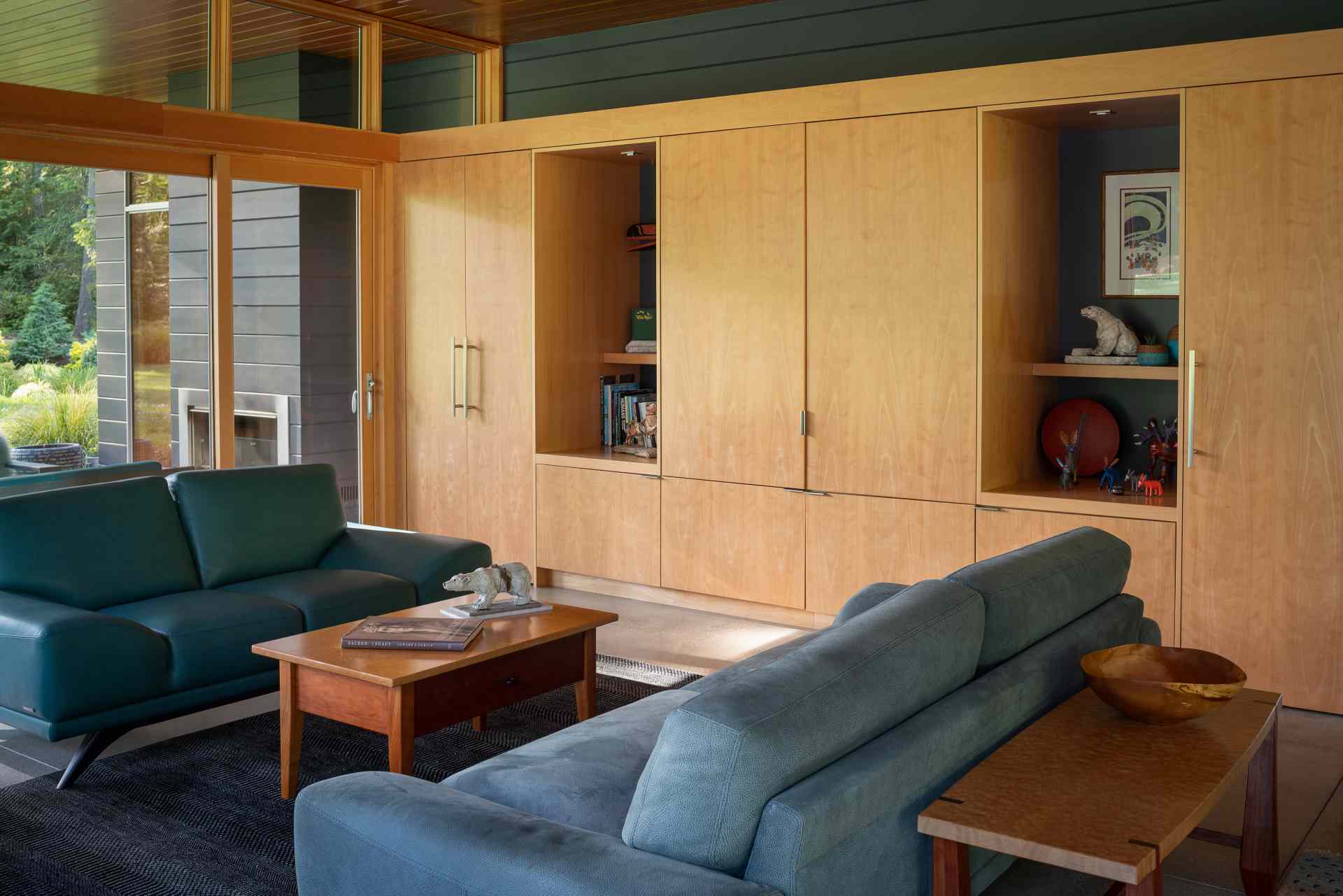 In this living room, natural light floods the interior, while a fireplace keeps things warm and custom-designed cabinetry hides the TV and a workspace when not in use.