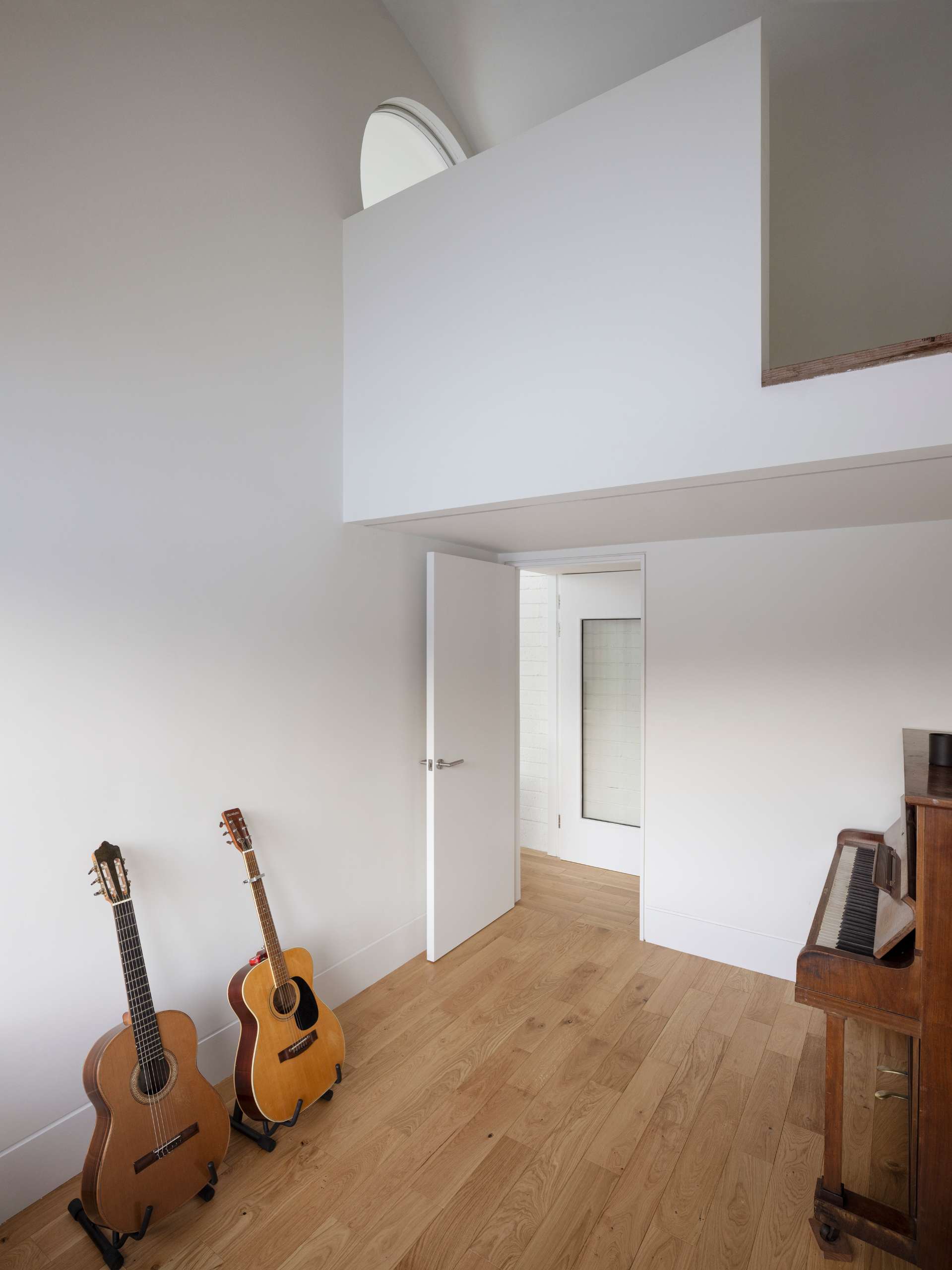 A contemporary home with a bright music room with white walls and wood flooring.