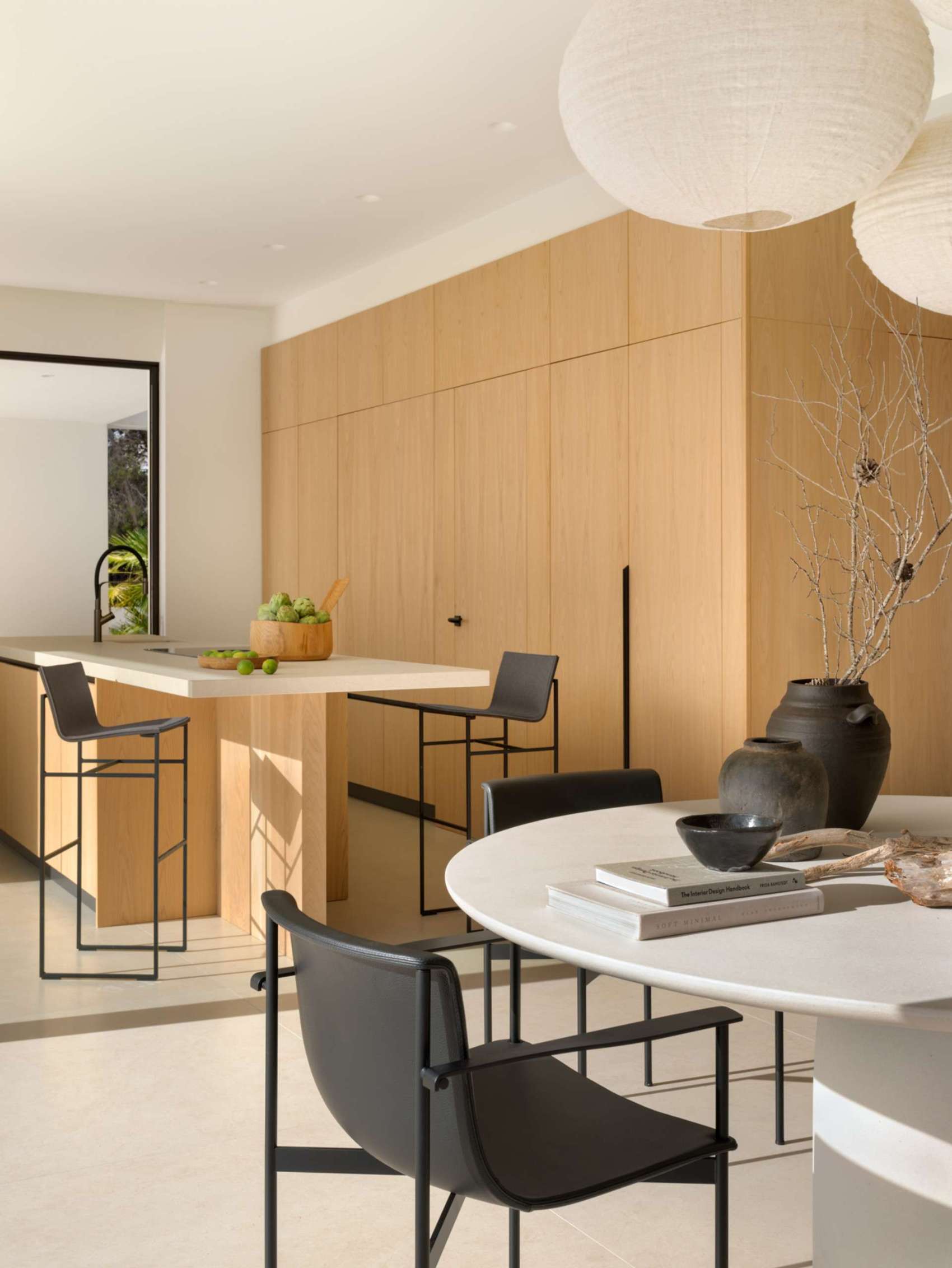 This light-filled kitchen embraces simplicity with flat-front oak cabinetry and a sleek stone topped island. Floor-to-ceiling doors blur the line between indoors and out, creating an airy transition to the natural landscape beyond.