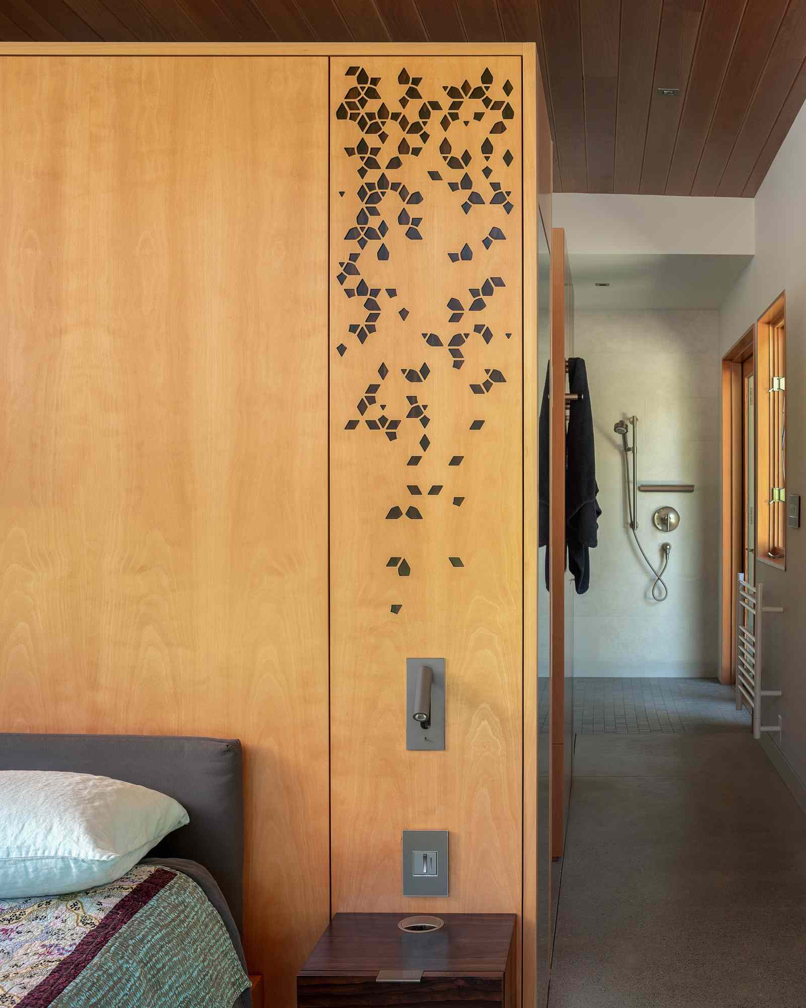 A modern primary bedroom with wood accent wall and pattern motifs.