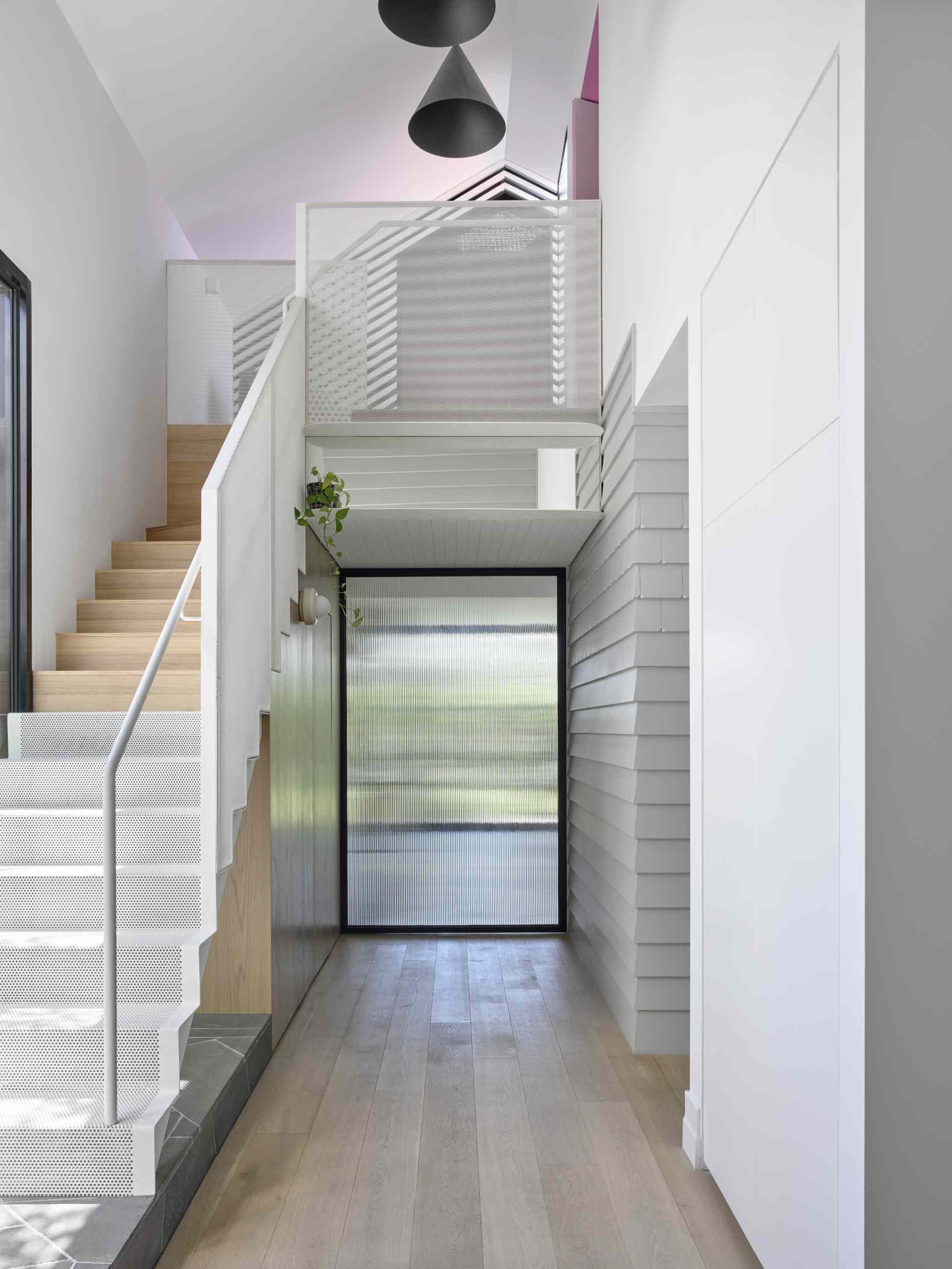 A perforated steel staircase leads to the upper level of the home.