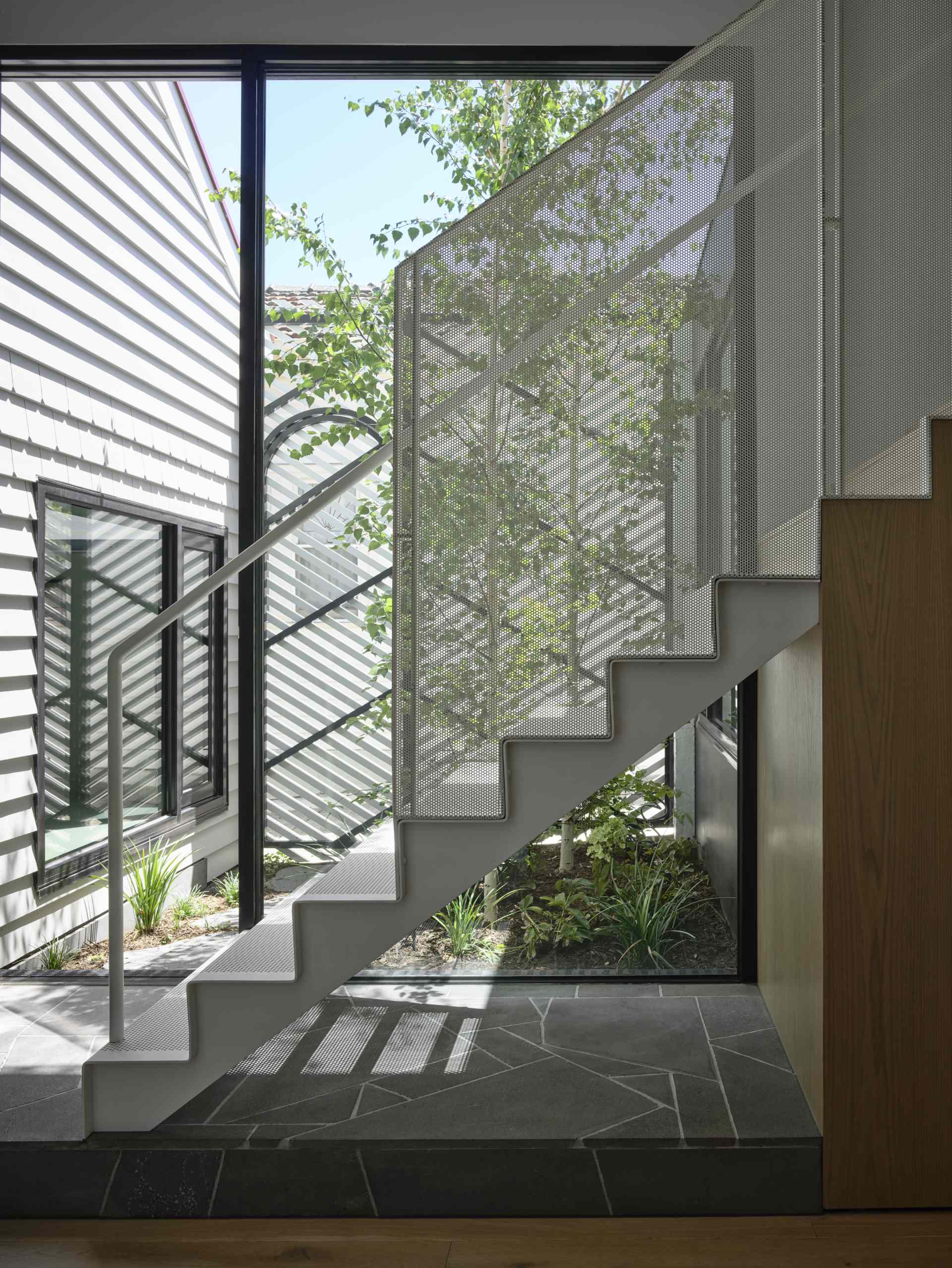 A perforated steel staircase leads to the upper level of the home.