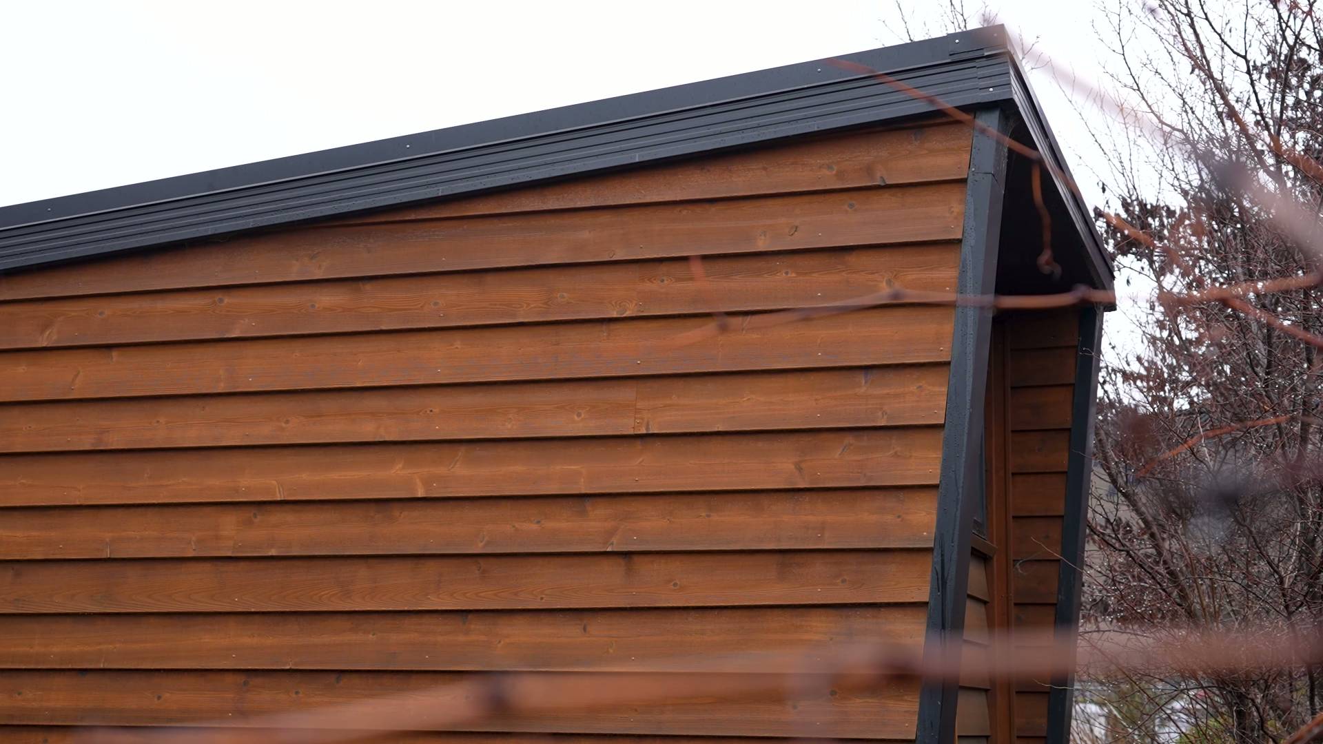 The exterior of this tiny home is clad in timber with black detailing along the edges, giving it a modern cabin feel.