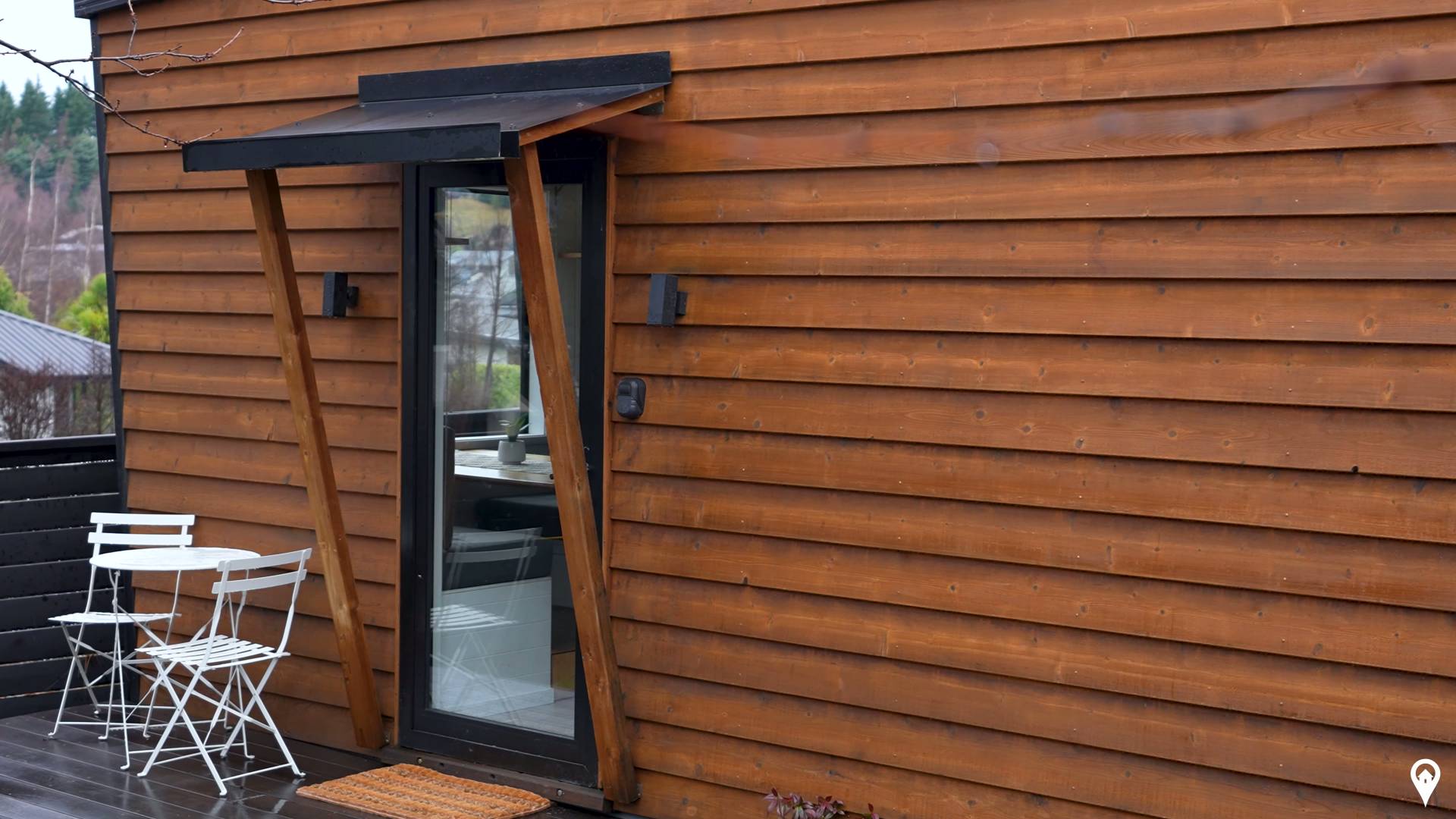 The exterior of this tiny home is clad in timber with black detailing along the edges, giving it a modern cabin feel.