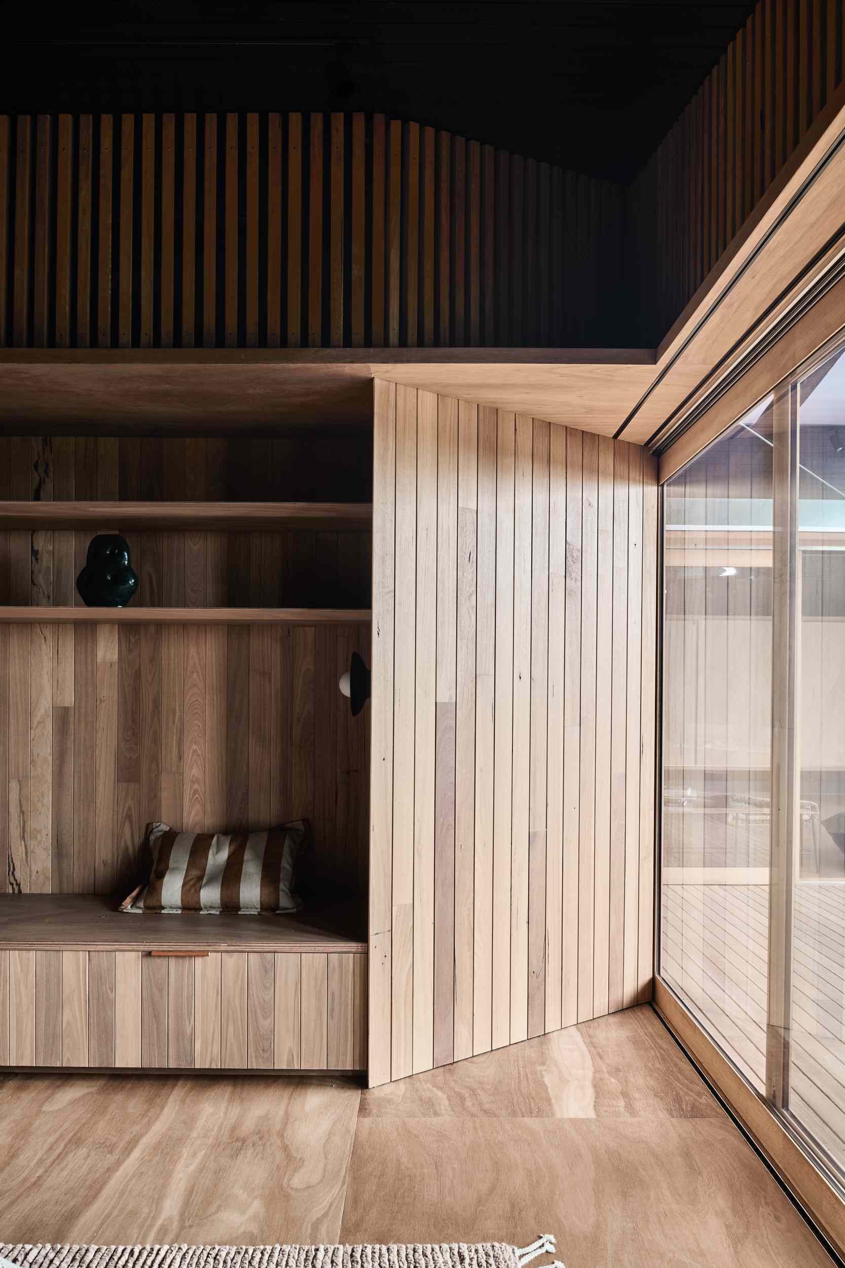 This bedroom is enveloped in warm timber tones, creating a serene, cocoon-like retreat. Custom cabinetry and integrated shelving offer seamless storage, while built-in seating adds comfort and functionality.