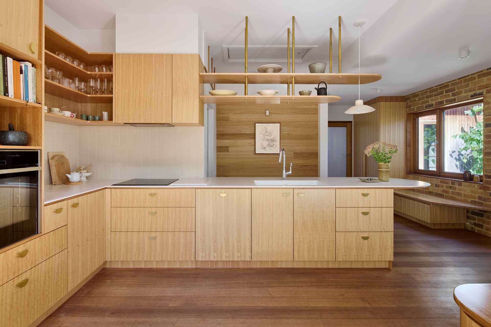 A contemporary kitchen with wood cabinets and white countertops, also includes a variety of seating options in the form of built-in benches.